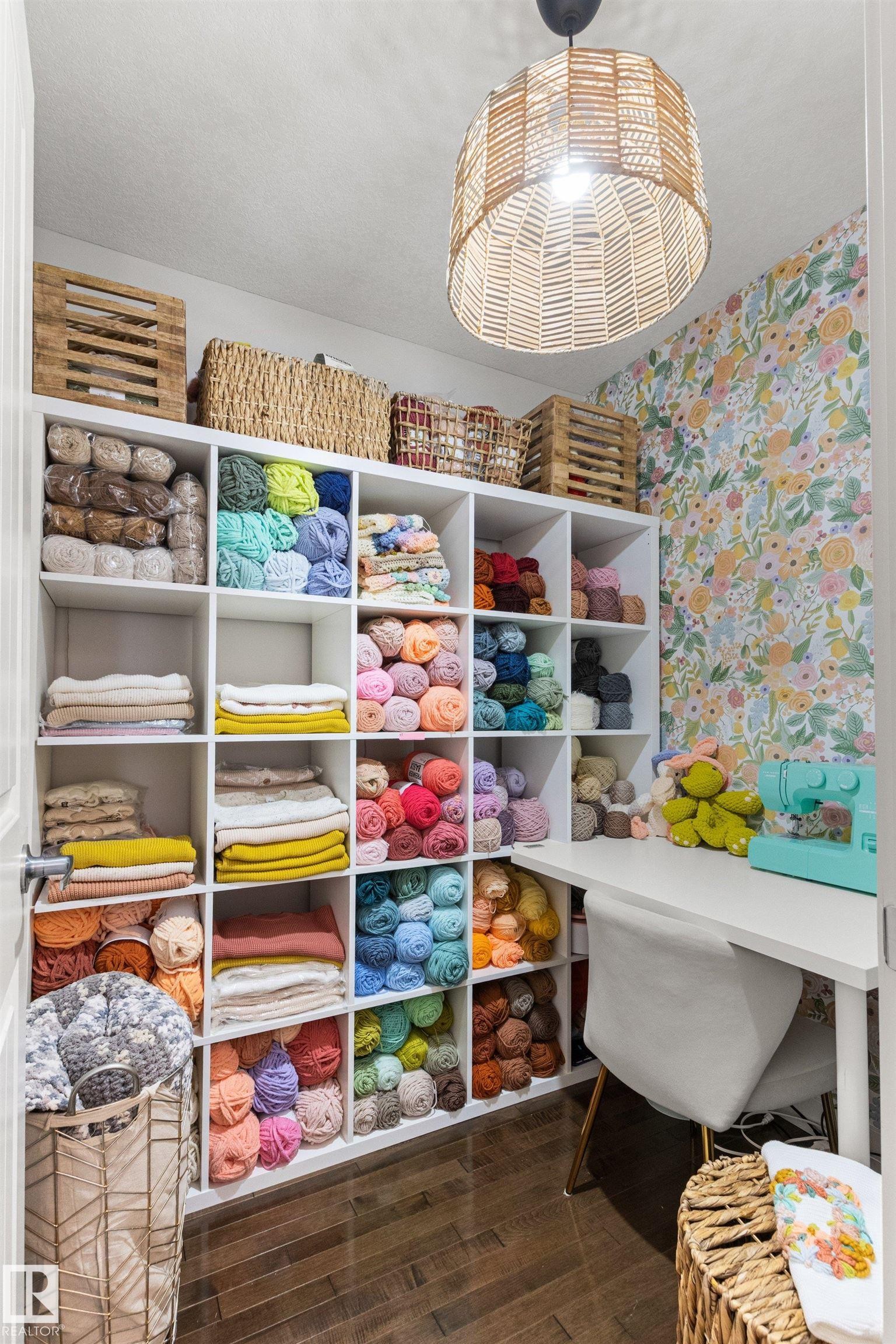 This area features extensive white shelving units, a light-toned wooden floor, and a patterned wallpaper - 38 Hewitt Circle, Spruce Grove, AB - Indoor