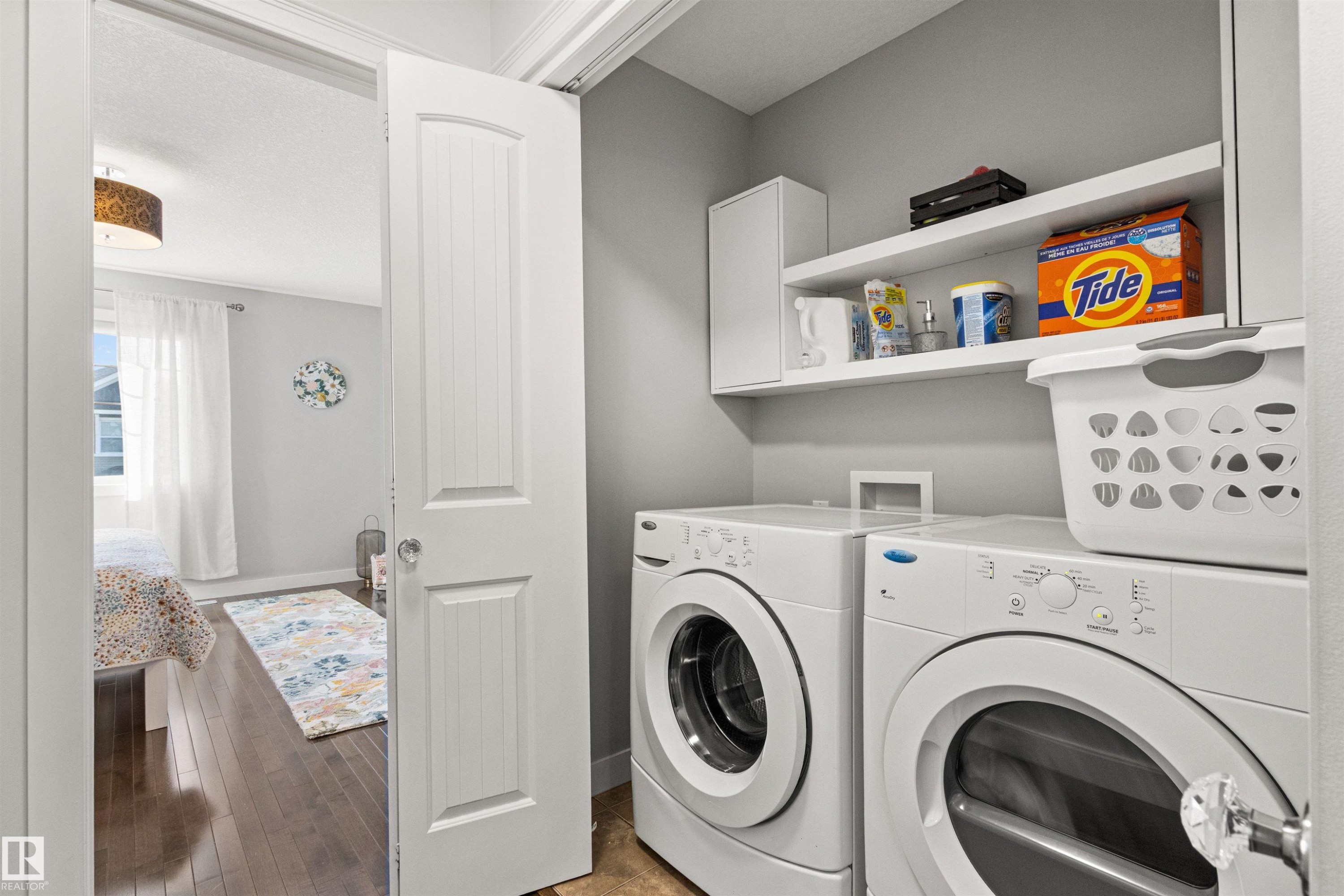 Laundry area featuring a front-load washer and dryer, with shelving and cabinetry for storage - 38 Hewitt Circle, Spruce Grove, AB - Indoor Photo Showing Laundry Room