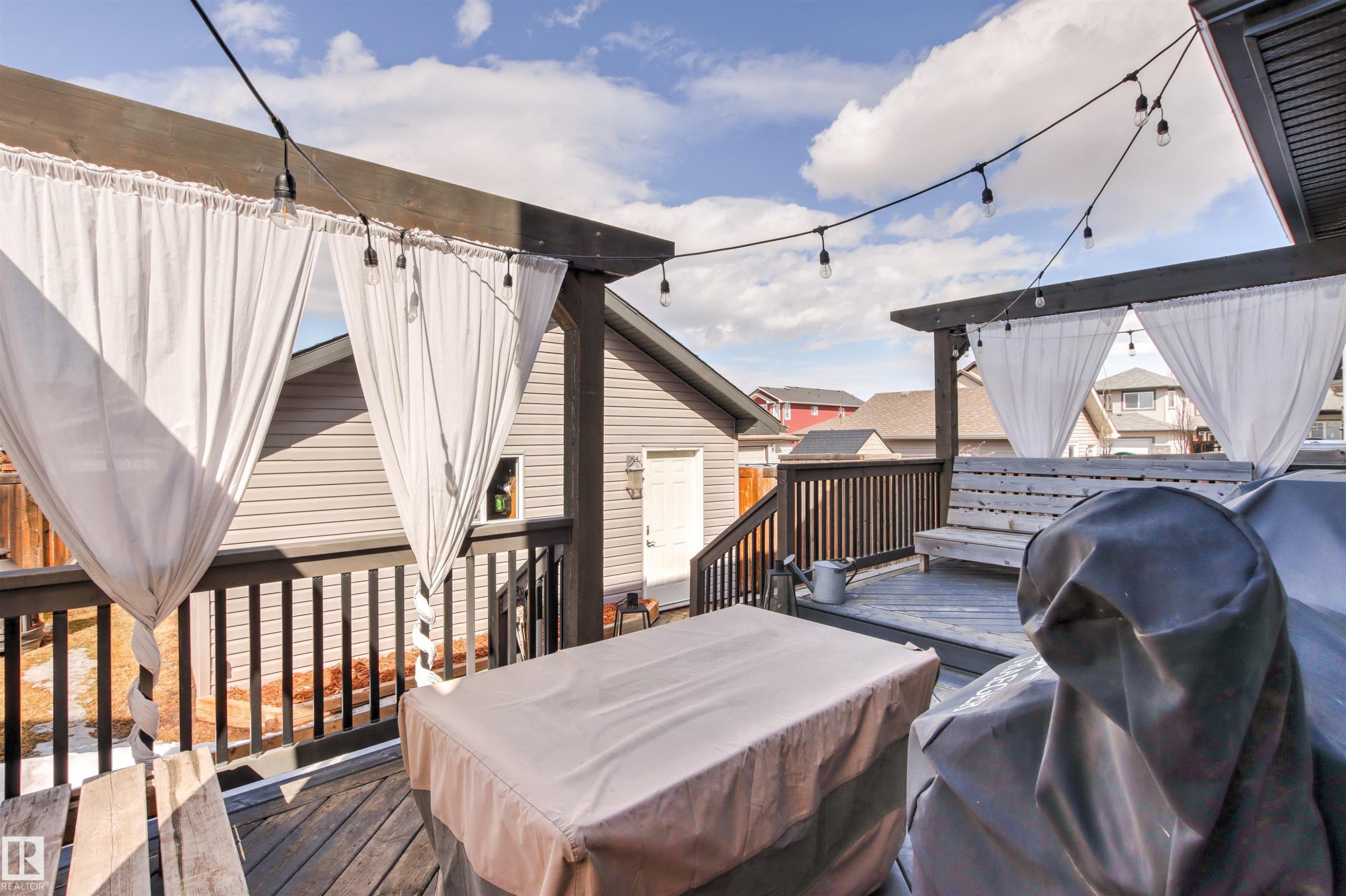 The property features an outdoor deck with dark wood railings and string lights - 38 Hewitt Circle, Spruce Grove, AB - Outdoor With Deck Patio Veranda With Exterior