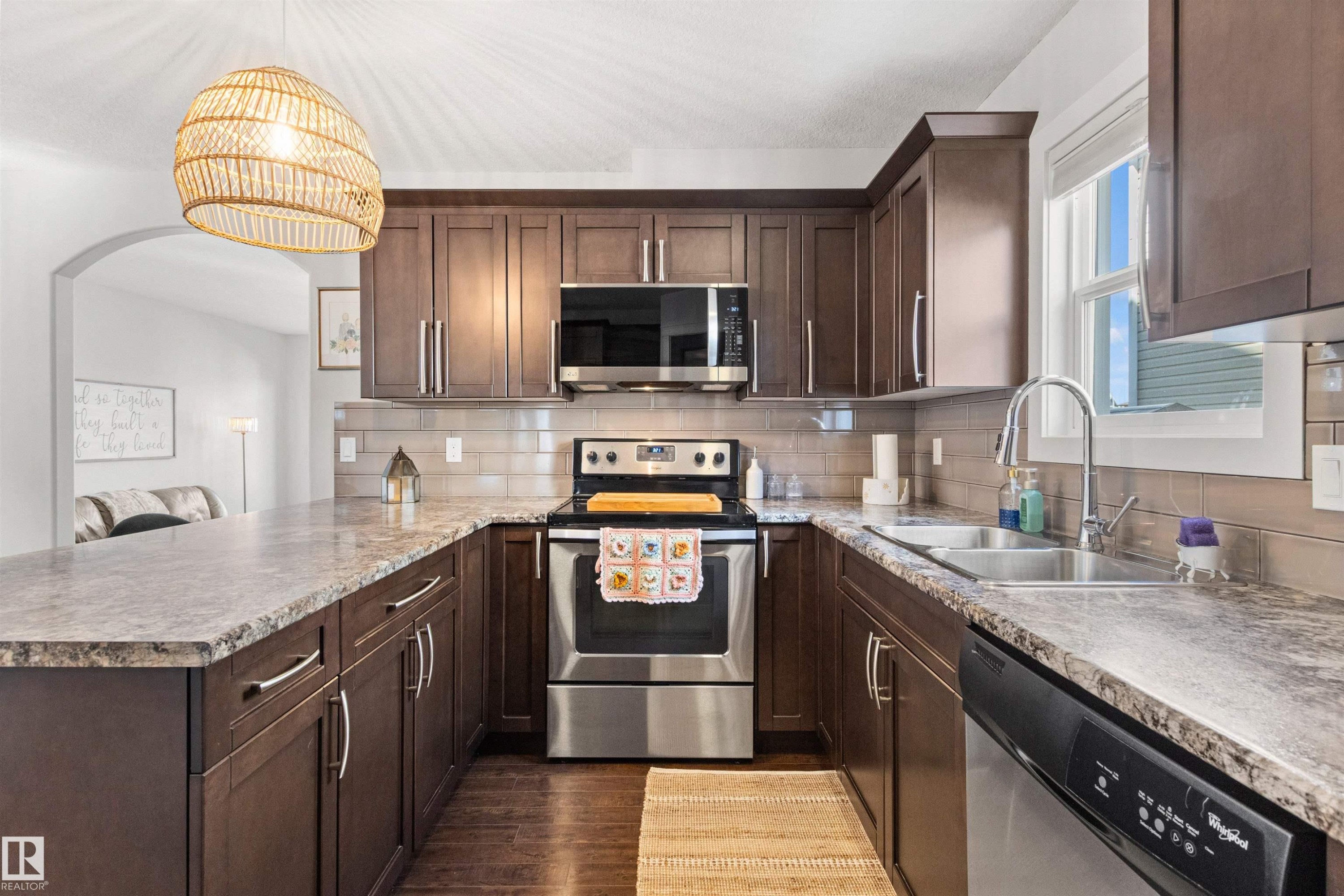 The kitchen features dark wood cabinetry, stainless steel appliances, a double basin sink, and ample countertop space - 38 Hewitt Circle, Spruce Grove, AB - Indoor Photo Showing Kitchen With Stainless Steel Kitchen With Double Sink With Upgraded Kitchen