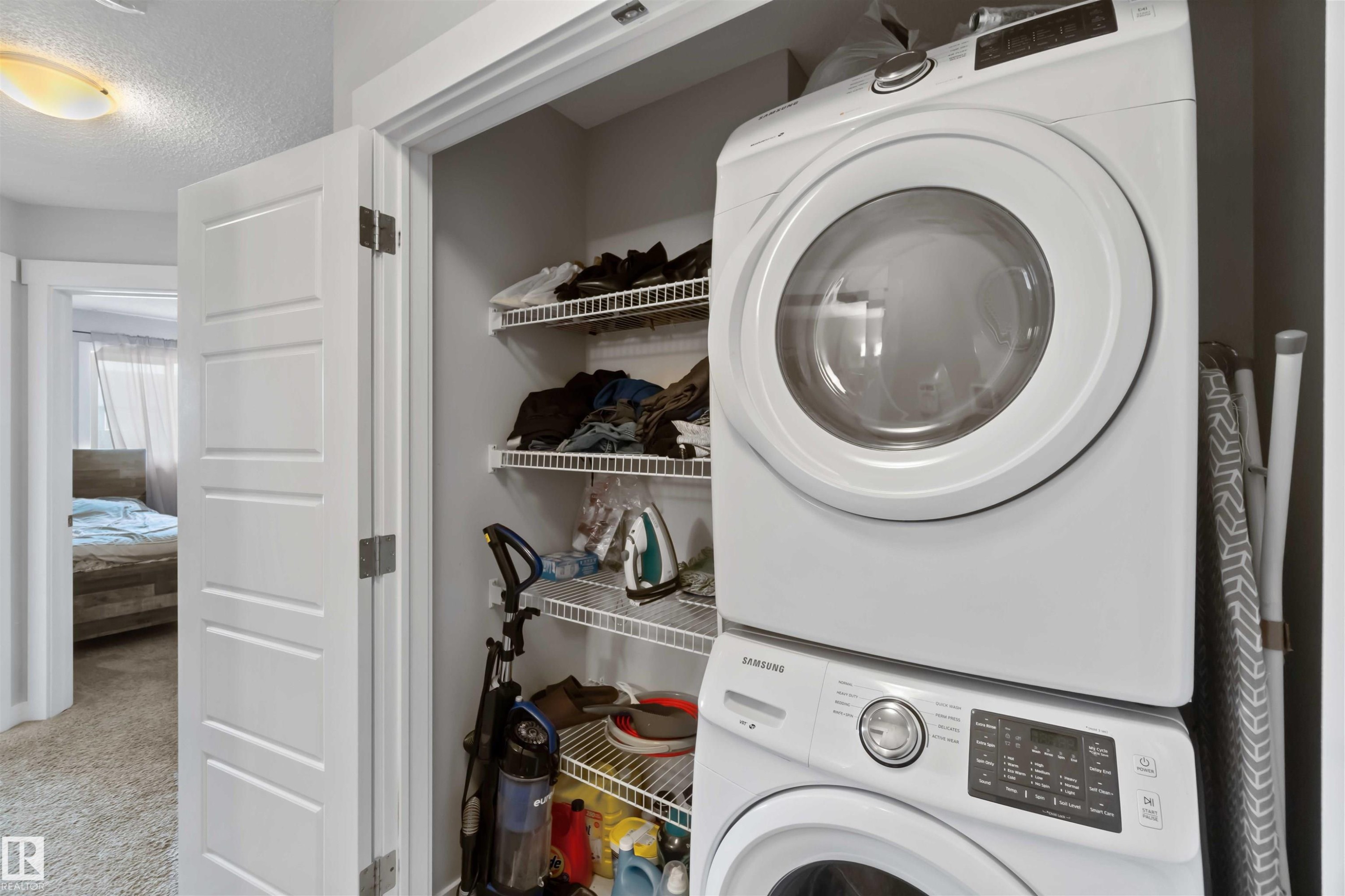 This property features a dedicated laundry area with a stacked washer and dryer, along with wire shelving for storage - 2725 Orchards Road, Edmonton, AB - Indoor Photo Showing Laundry Room