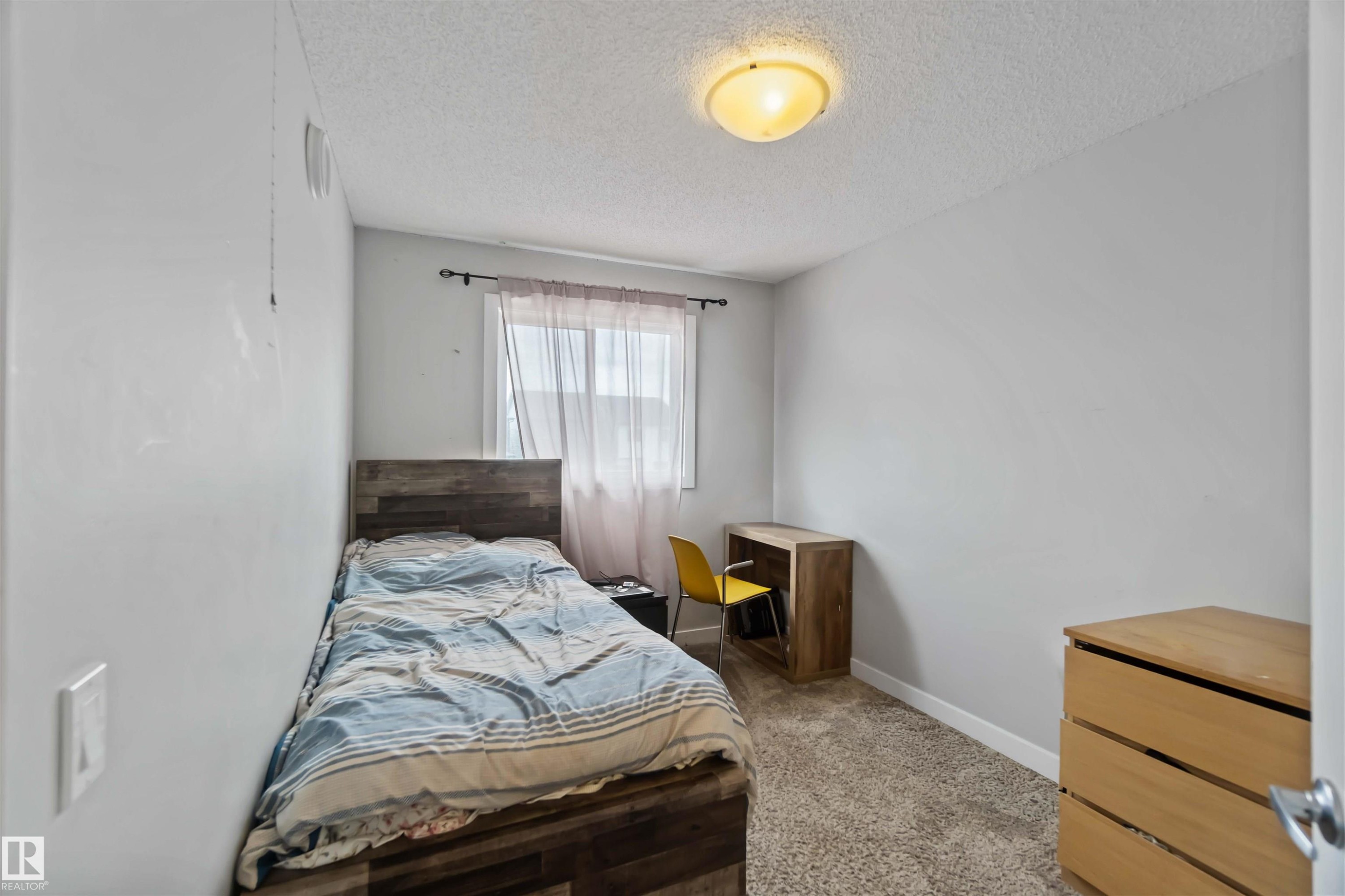 This room features light grey walls and carpeted flooring, with a window providing natural light - 2725 Orchards Road, Edmonton, AB - Indoor Photo Showing Bedroom