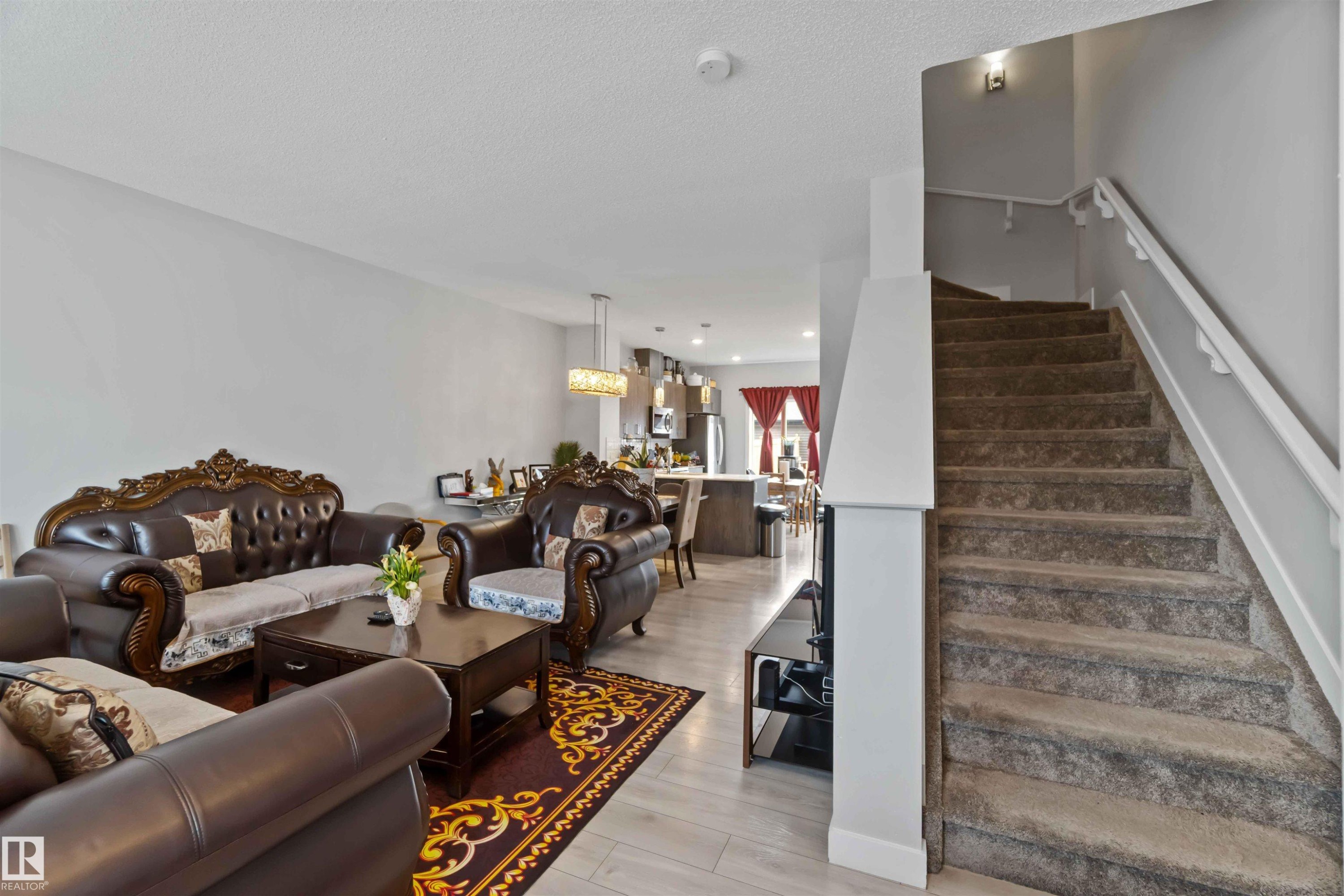 Open concept living area featuring light-colored flooring, a carpeted staircase with white railings, and recessed lighting - 2725 Orchards Road, Edmonton, AB - Indoor Photo Showing Living Room