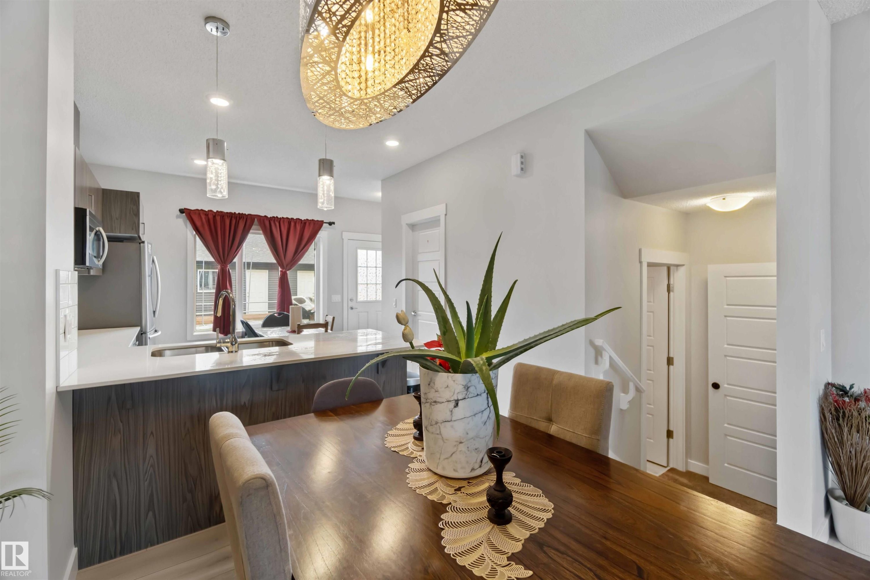 Dining area featuring a dark wood table, a decorative overhead light fixture, and pendant lighting - 2725 Orchards Road, Edmonton, AB - Indoor Photo Showing Dining Room