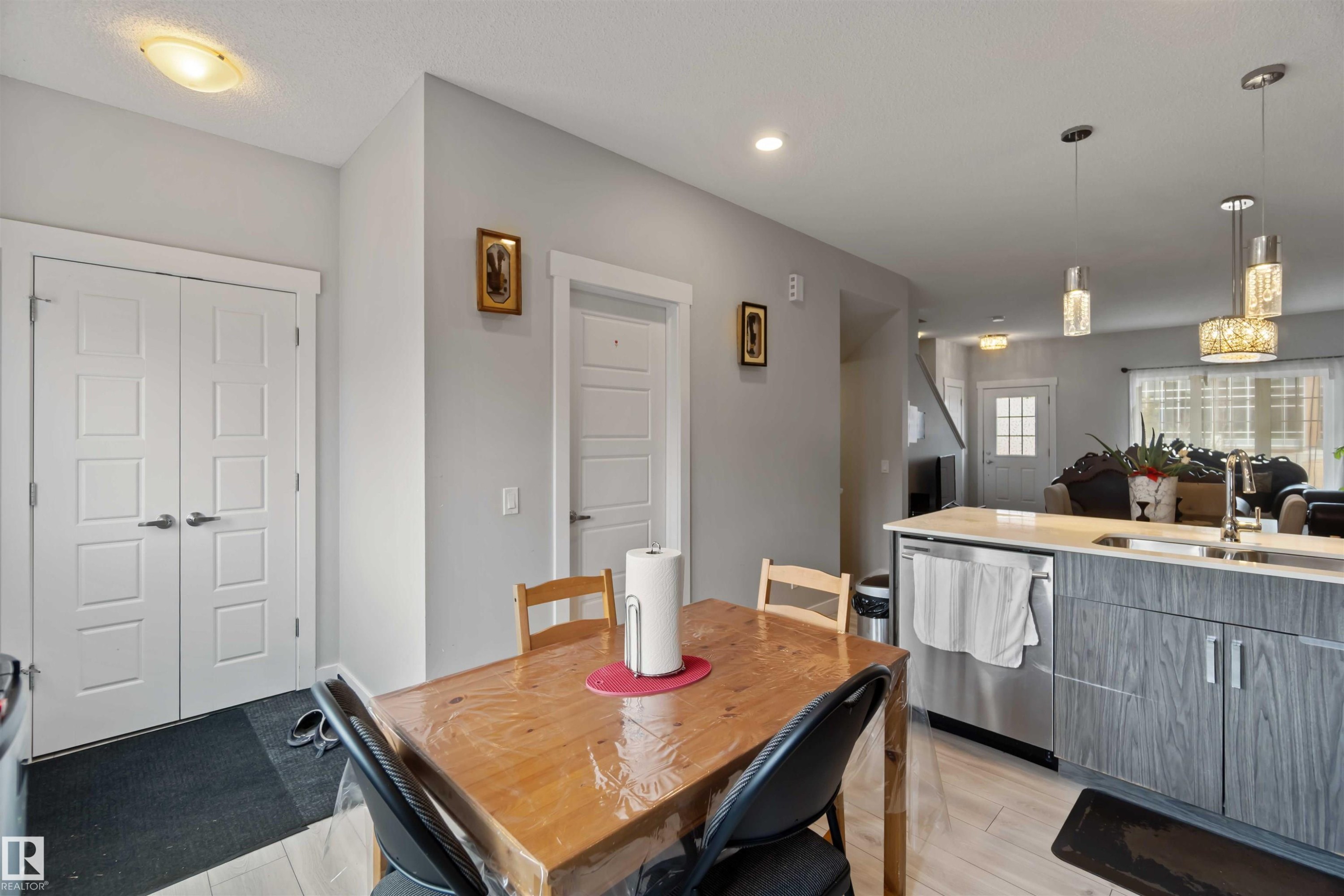 The dining area features a wooden table and chairs, with recessed lighting and a ceiling light fixture - 2725 Orchards Road, Edmonton, AB - Indoor