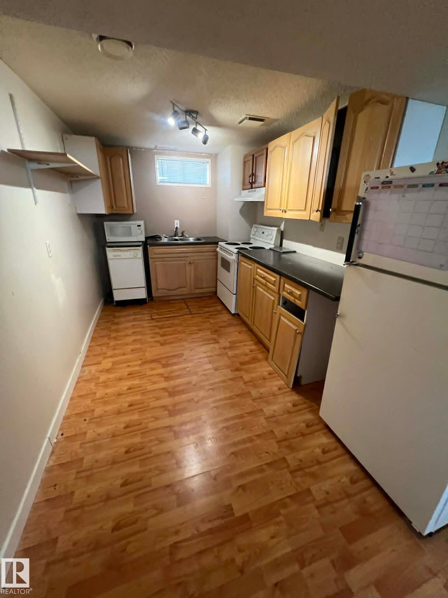 Kitchen area featuring wood-finish flooring, light wood cabinetry, and a window for natural light - 4129 134A Avenue Nw, Edmonton, AB - Indoor Photo Showing Kitchen