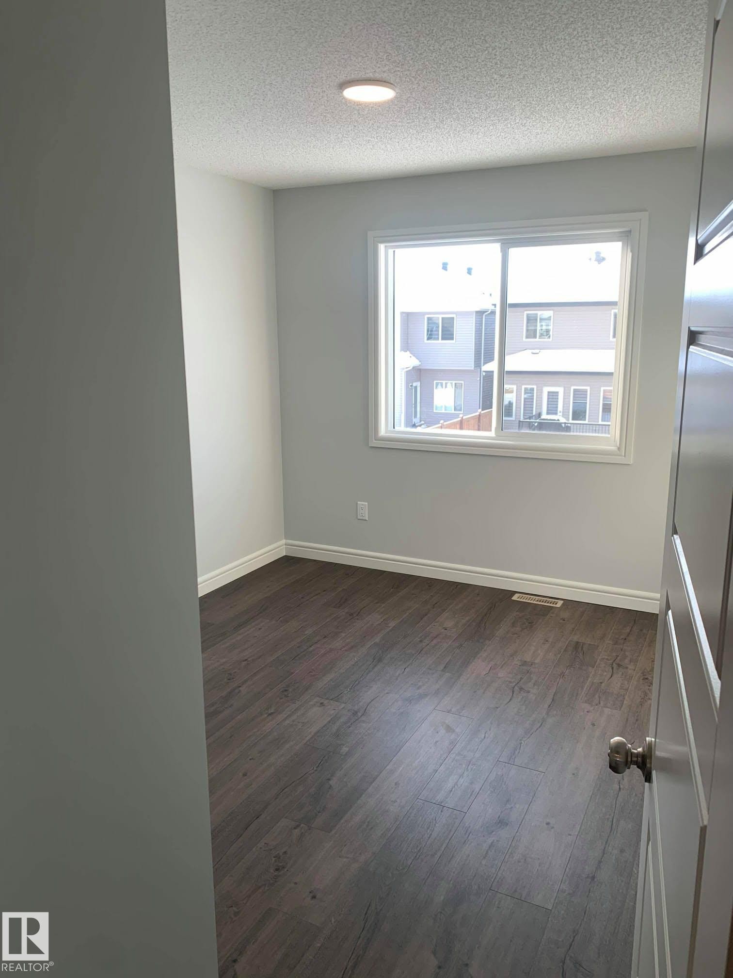 Room featuring wood-finish flooring, a white-framed window, recessed ceiling lighting, and white baseboards - 4129 134A Avenue Nw, Edmonton, AB - Indoor Photo Showing Other Room
