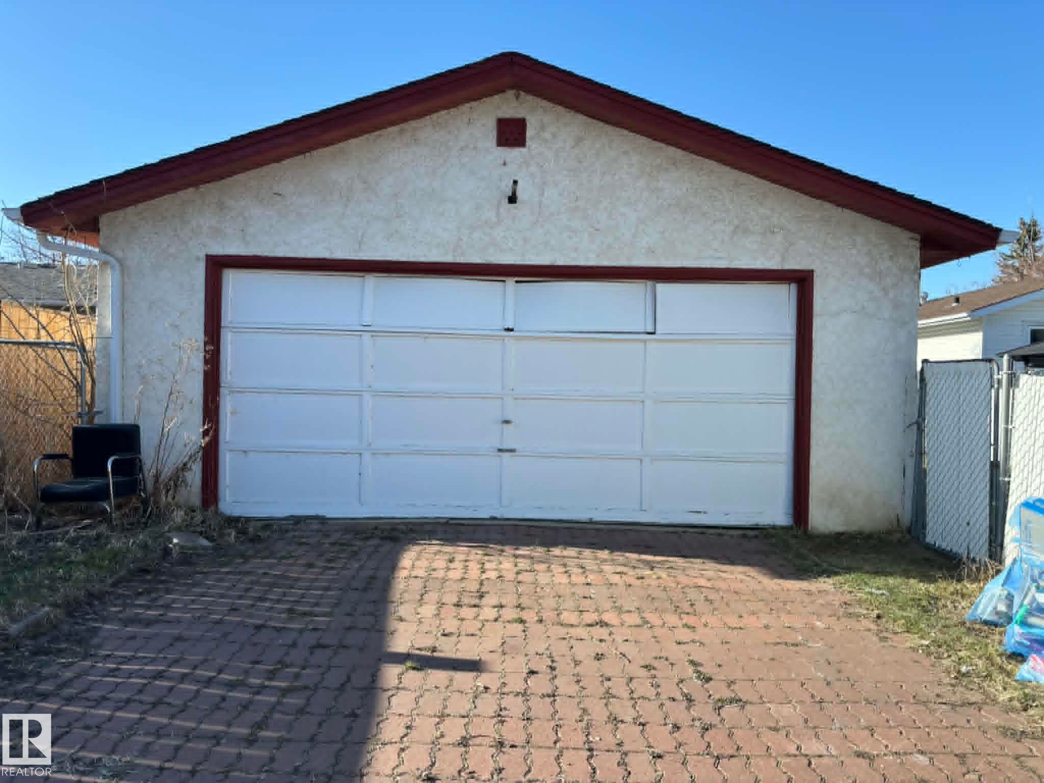 Detached garage featuring a white sectional door, stucco exterior, and a red shingle roof - 4129 134A Avenue Nw, Edmonton, AB - Outdoor