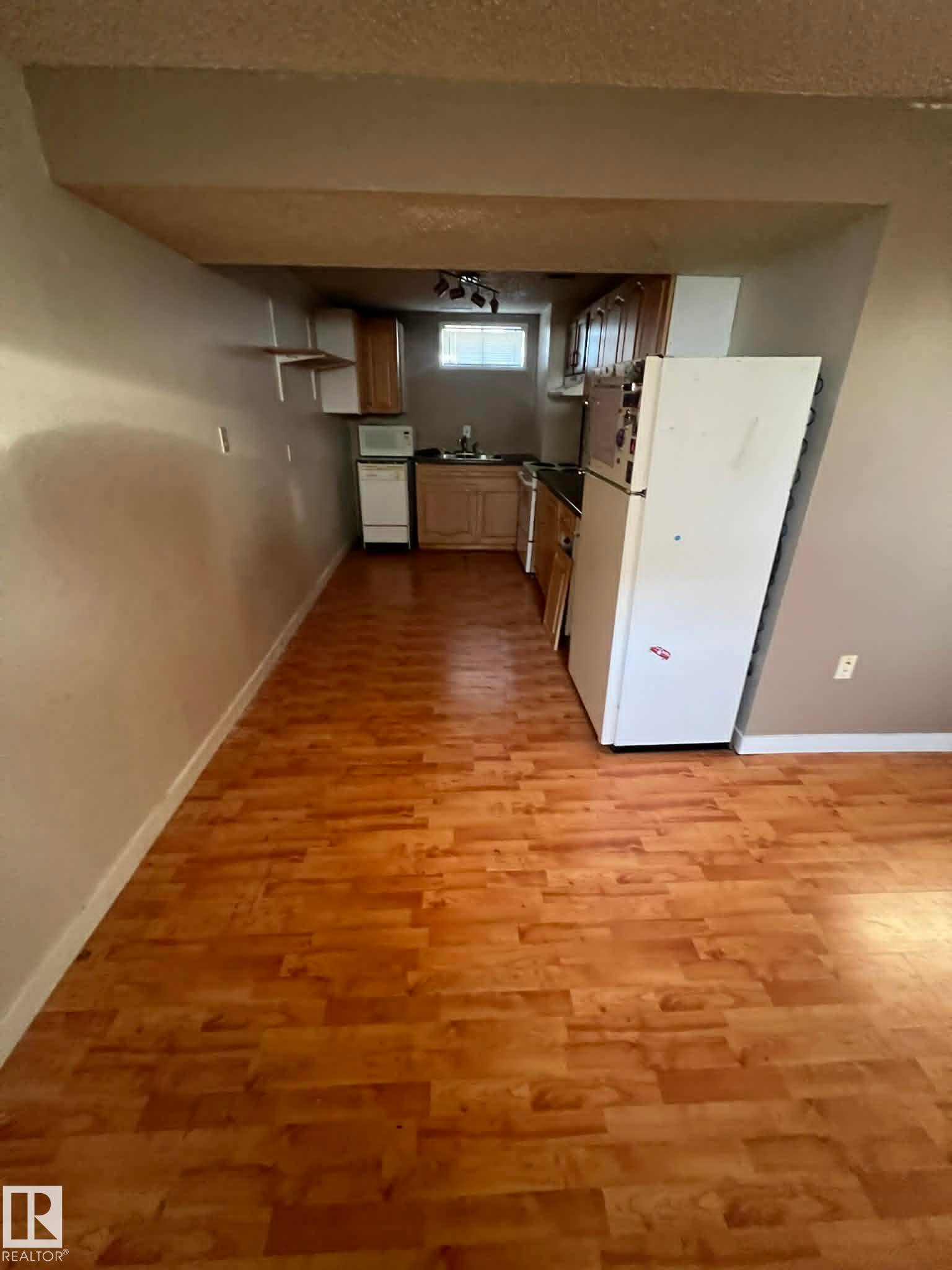Wood-finish flooring extends throughout this open-concept space featuring a compact kitchen - 4129 134A Avenue Nw, Edmonton, AB - Indoor Photo Showing Other Room