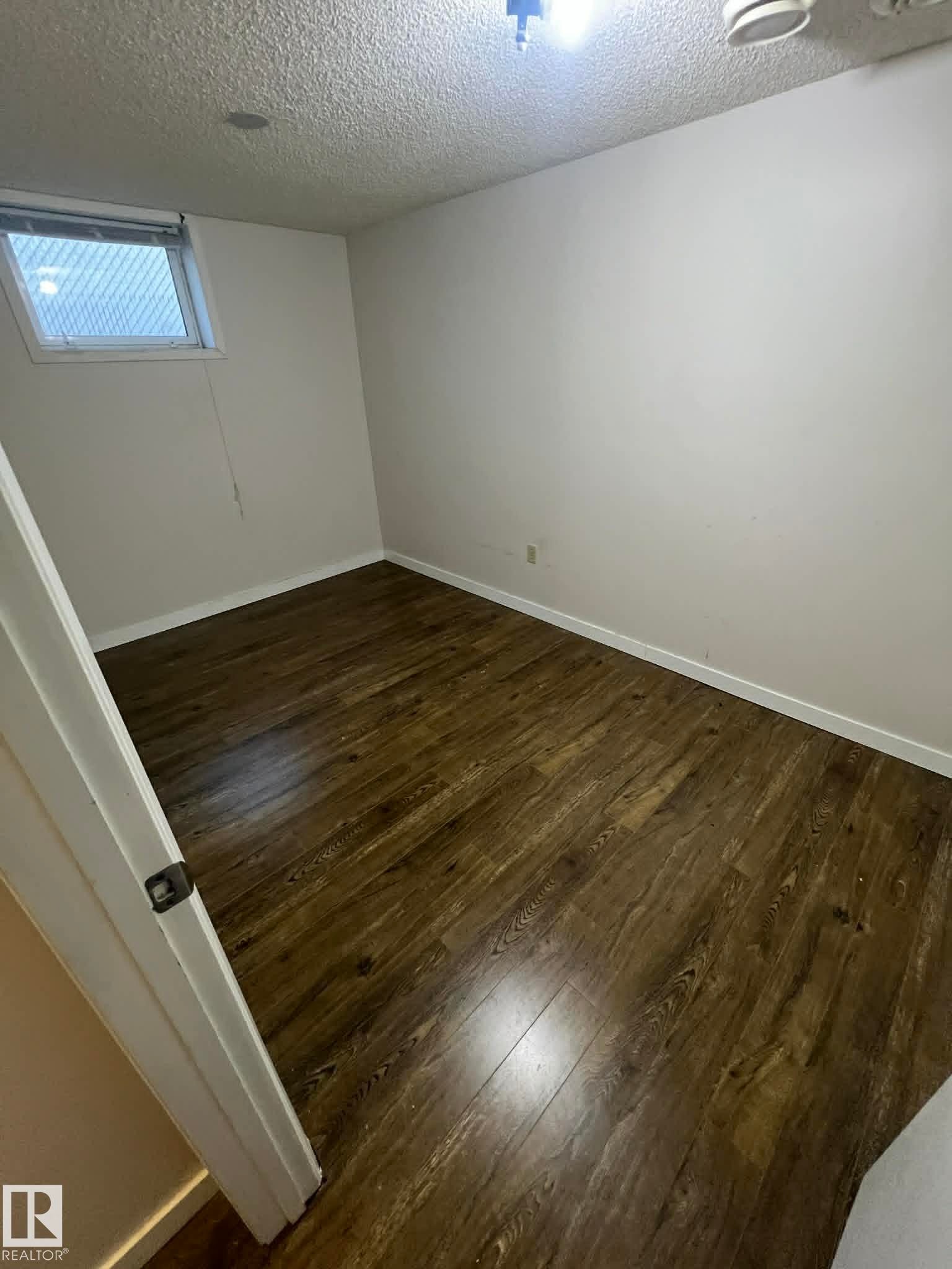 Room featuring wood-finish flooring, white walls, and a textured ceiling - 4129 134A Avenue Nw, Edmonton, AB - Indoor Photo Showing Other Room
