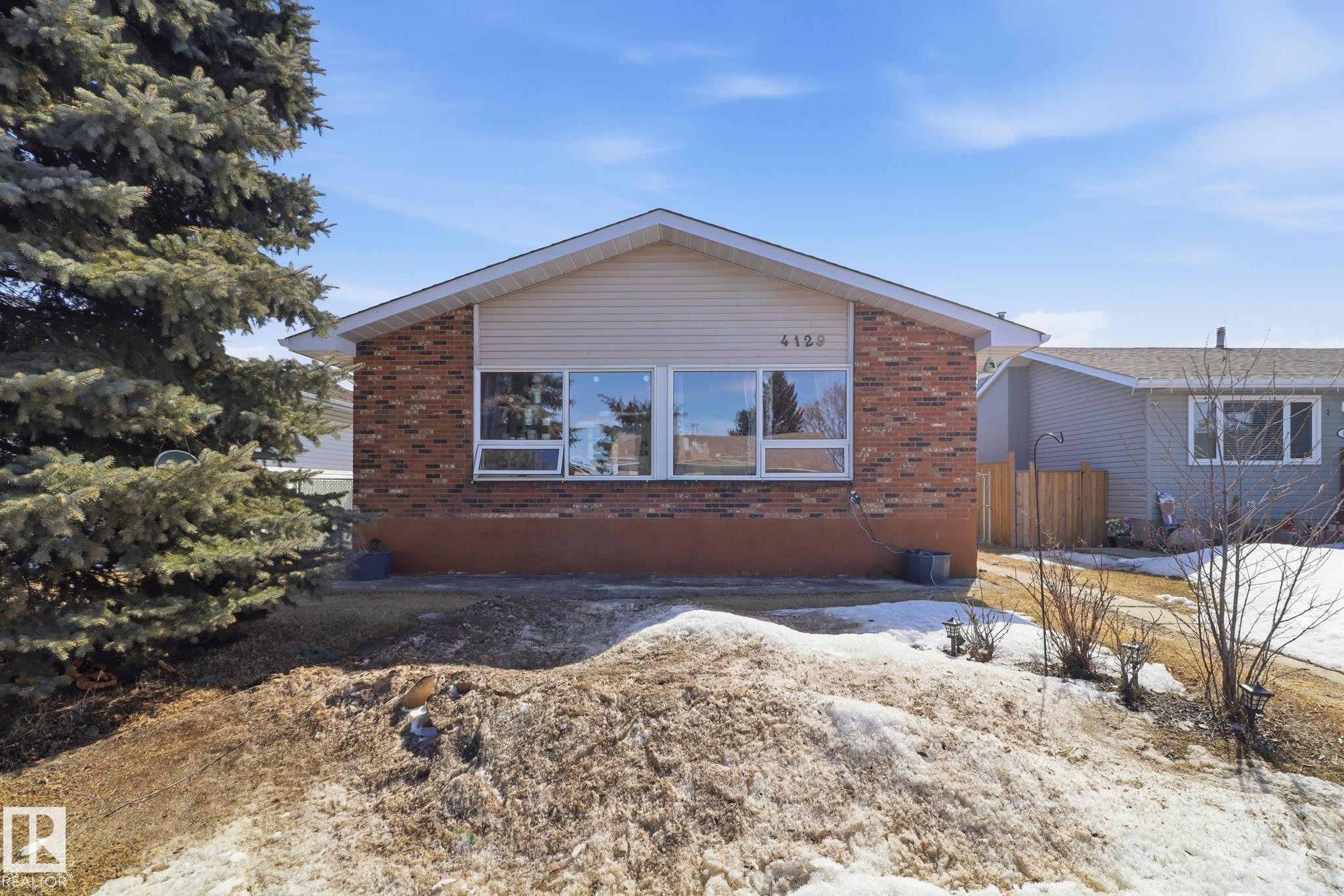 The property features a brick and siding exterior, with a prominent front window - 4129 134A Avenue Nw, Edmonton, AB - Outdoor
