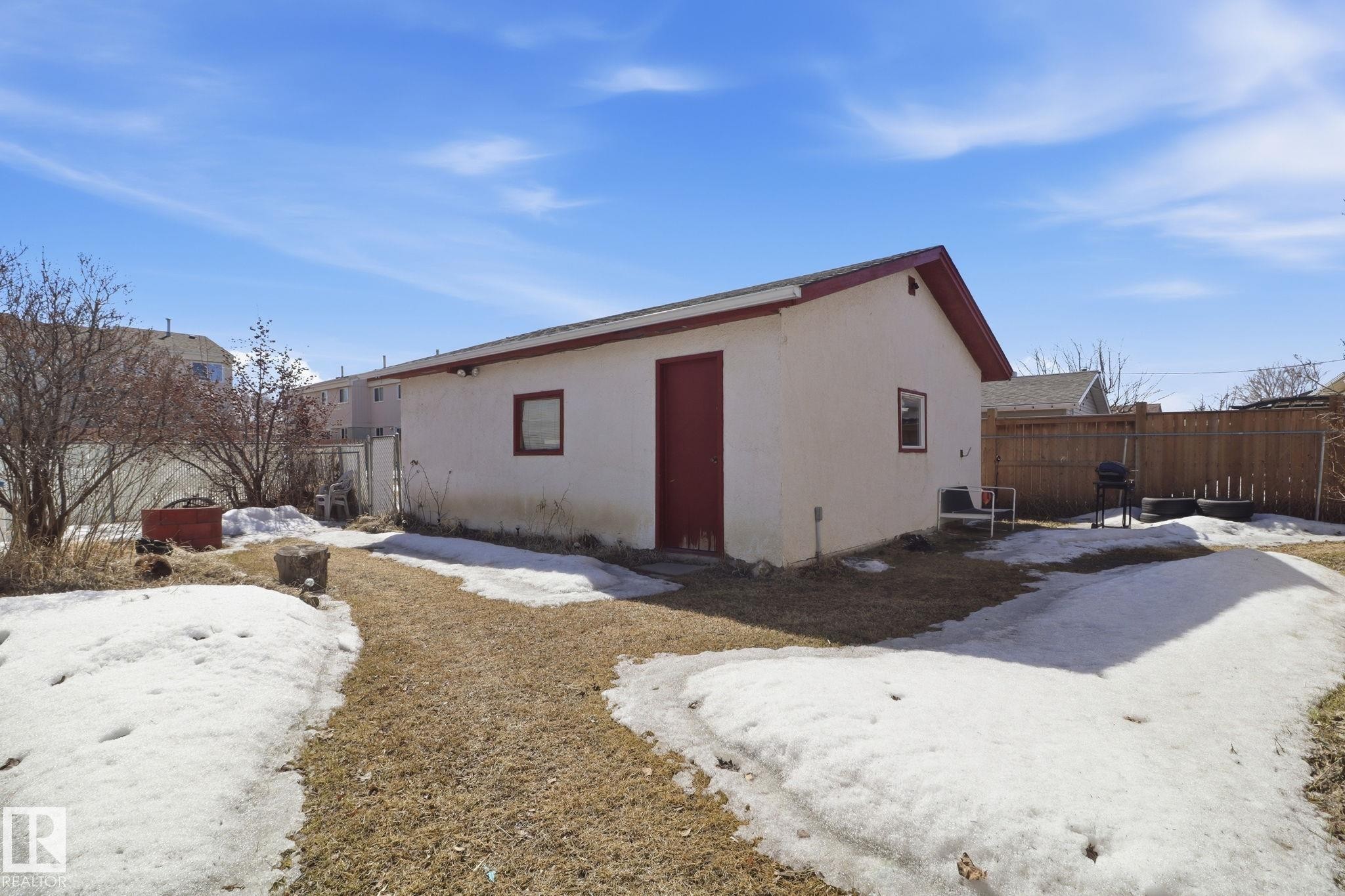 The property includes a detached garage with a red door and trim, and a fenced yard - 4129 134A Avenue Nw, Edmonton, AB - Outdoor