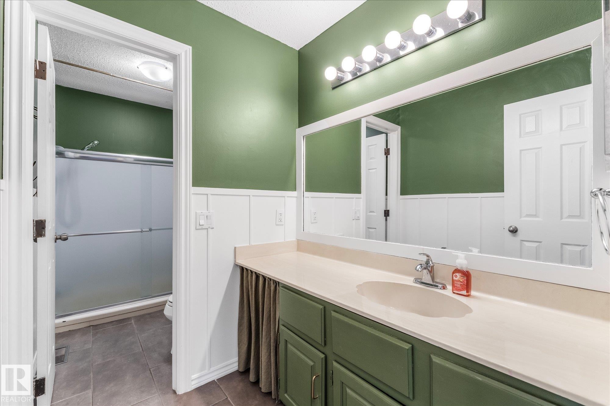 Bathroom featuring a vanity with a single sink, a large mirror, and a shower with a sliding glass door - 2626 49 Street, Edmonton, AB - Indoor Photo Showing Bathroom