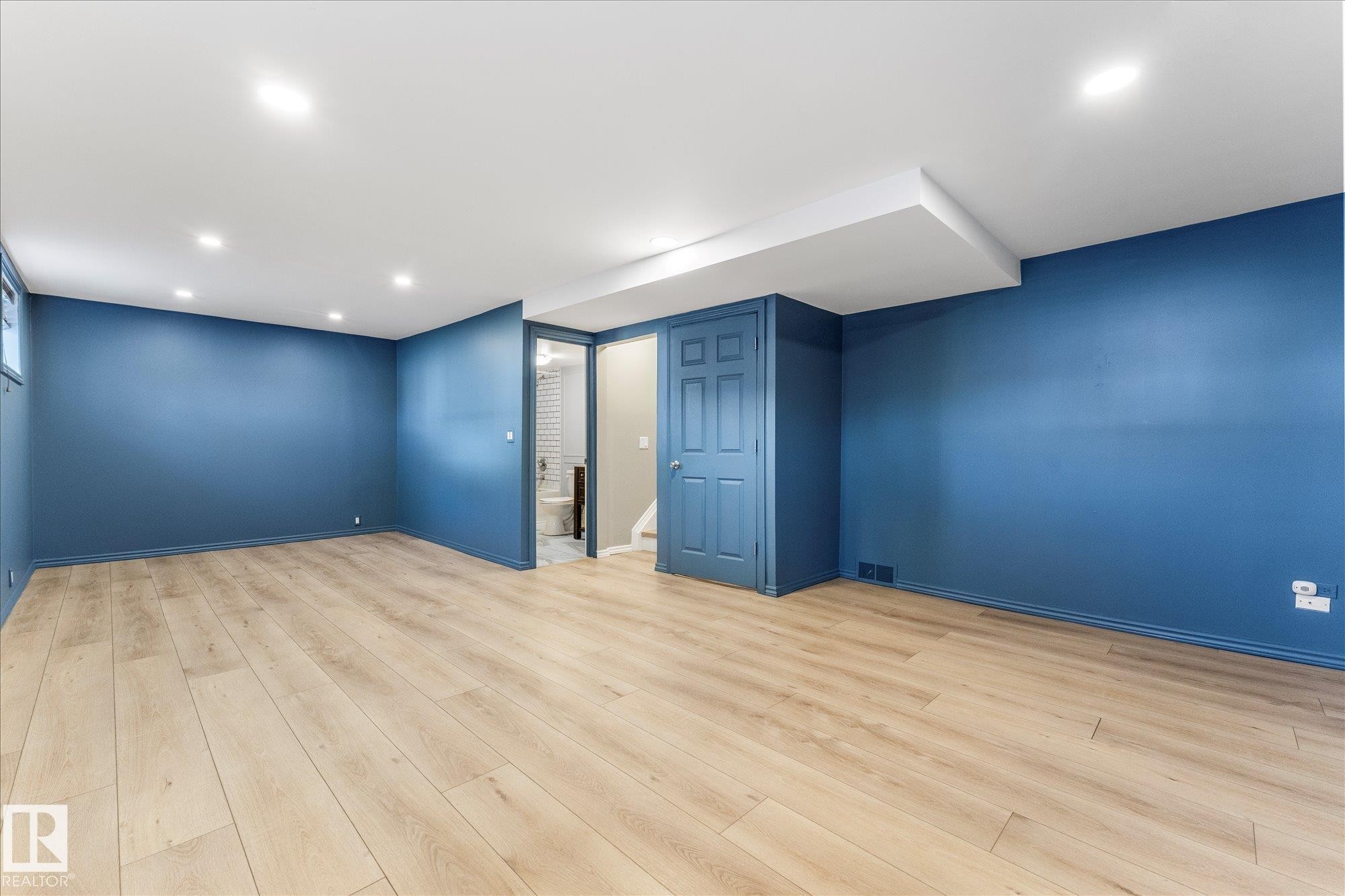 Spacious interior room featuring light-toned flooring, deep blue walls, recessed lighting, and a window - 2626 49 Street, Edmonton, AB - Indoor Photo Showing Other Room