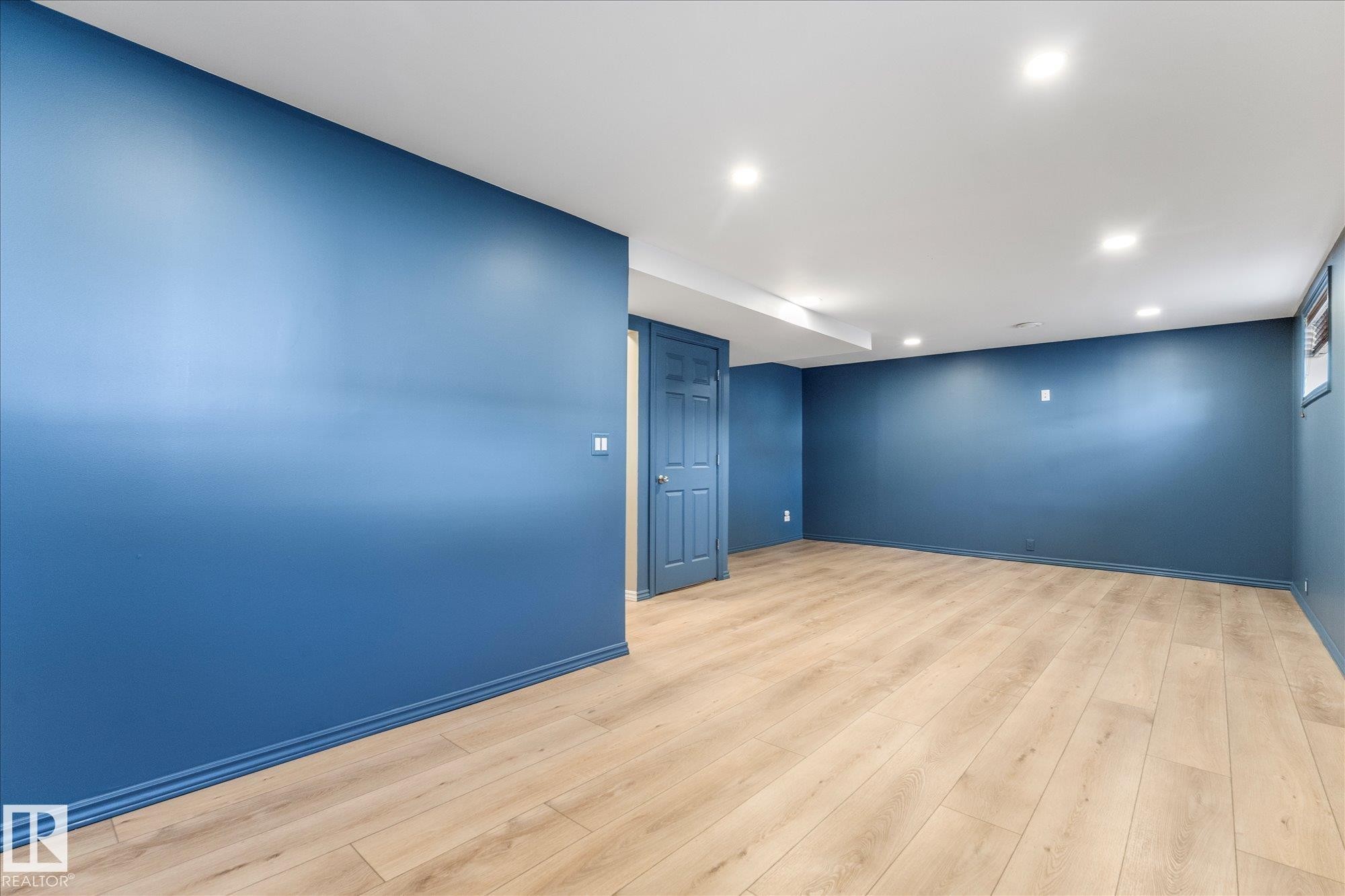 The property features light wood flooring and walls painted in a deep blue hue - 2626 49 Street, Edmonton, AB - Indoor