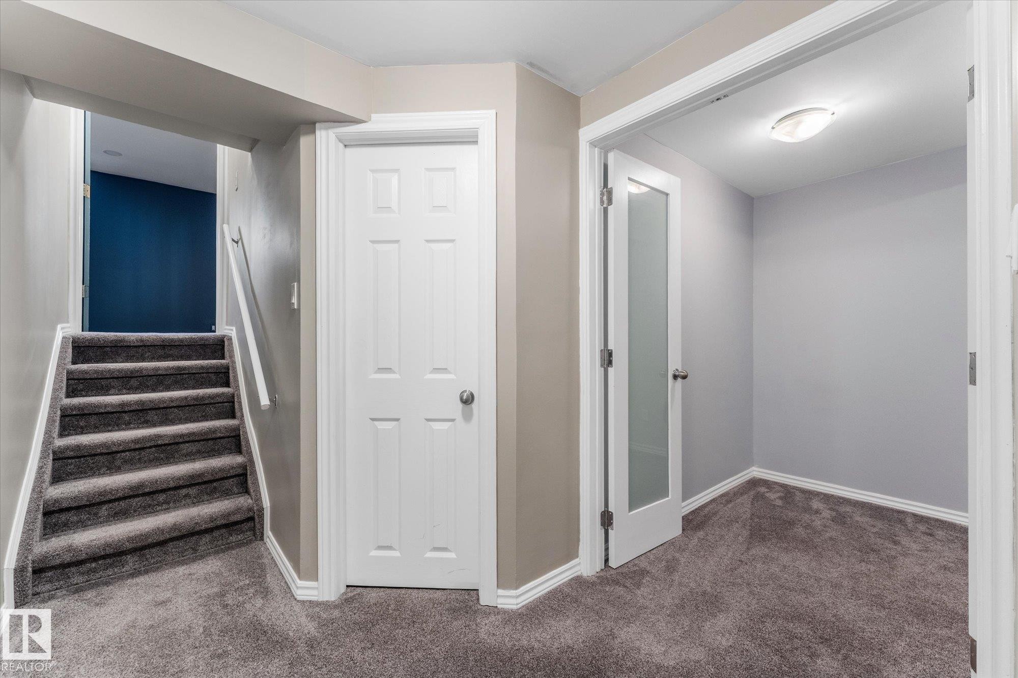 This interior space features gray carpeting, a staircase with a white handrail, and a white six-panel door - 2626 49 Street, Edmonton, AB - Indoor Photo Showing Other Room