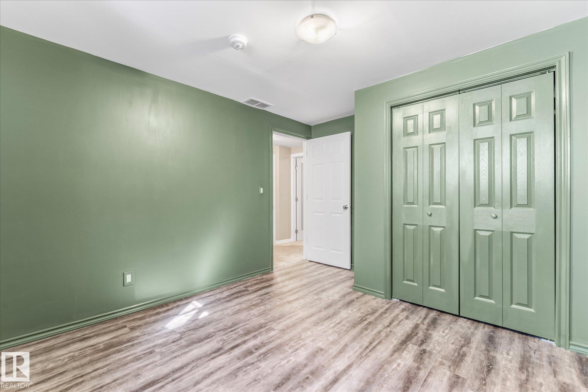 This room features stylish wood-look flooring and a light green wall color - 2626 49 Street, Edmonton, AB - Indoor Photo Showing Other Room