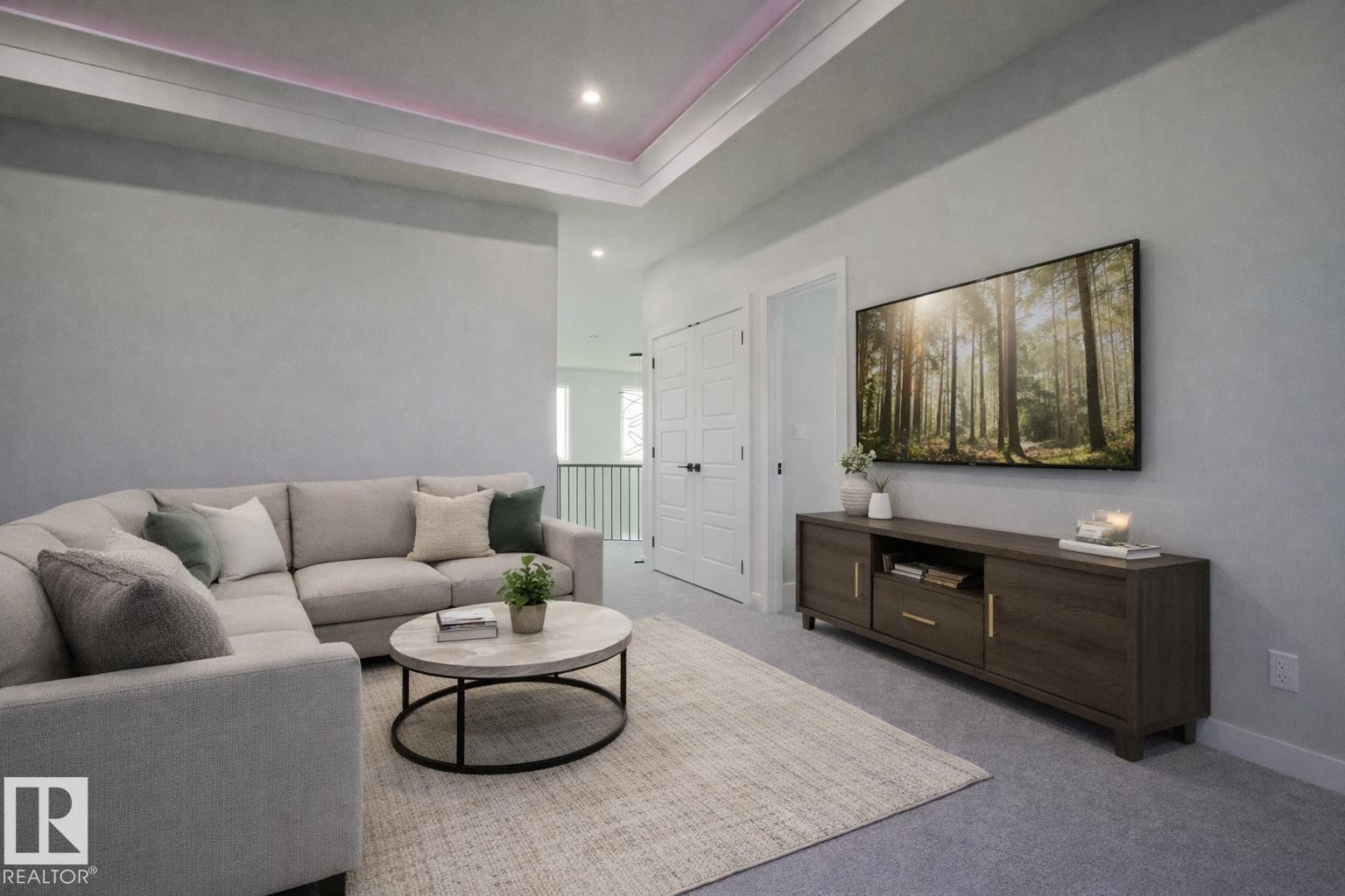 This inviting living area features soft carpeting, a recessed ceiling with ambient lighting, and a large wall-mounted television above a media console - Rural Leduc County, AB - Indoor Photo Showing Living Room