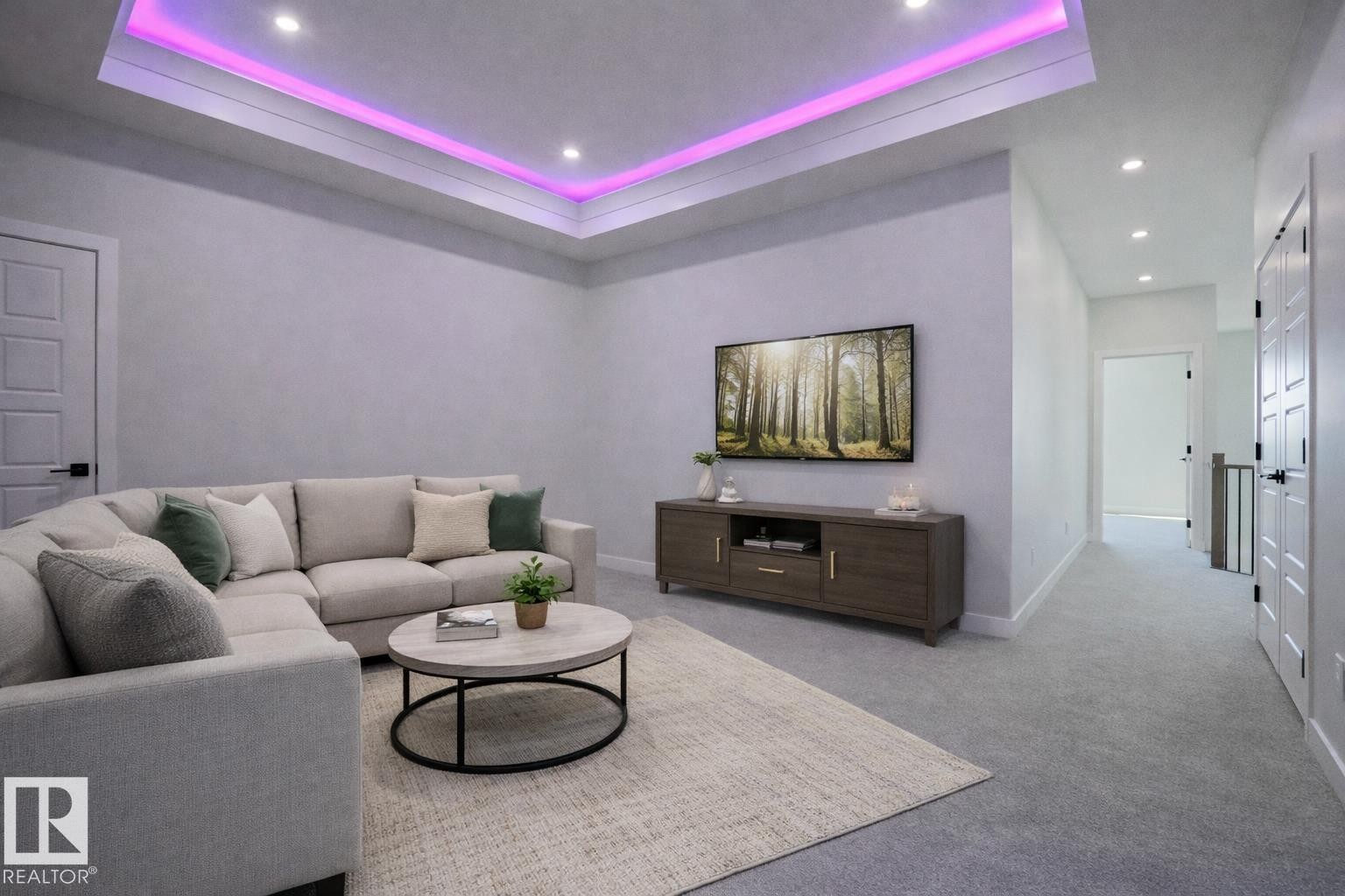 Living area featuring a tray ceiling with recessed lighting and accent lighting, light-colored carpeting, and a wall-mounted television - Rural Leduc County, AB - Indoor Photo Showing Living Room