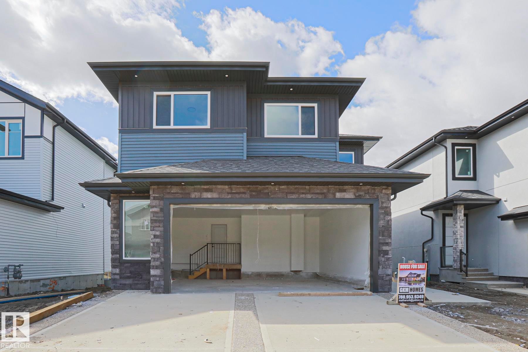 This property features a modern exterior with a multi-level design, incorporating both horizontal siding and stone accents - Rural Leduc County, AB - Outdoor