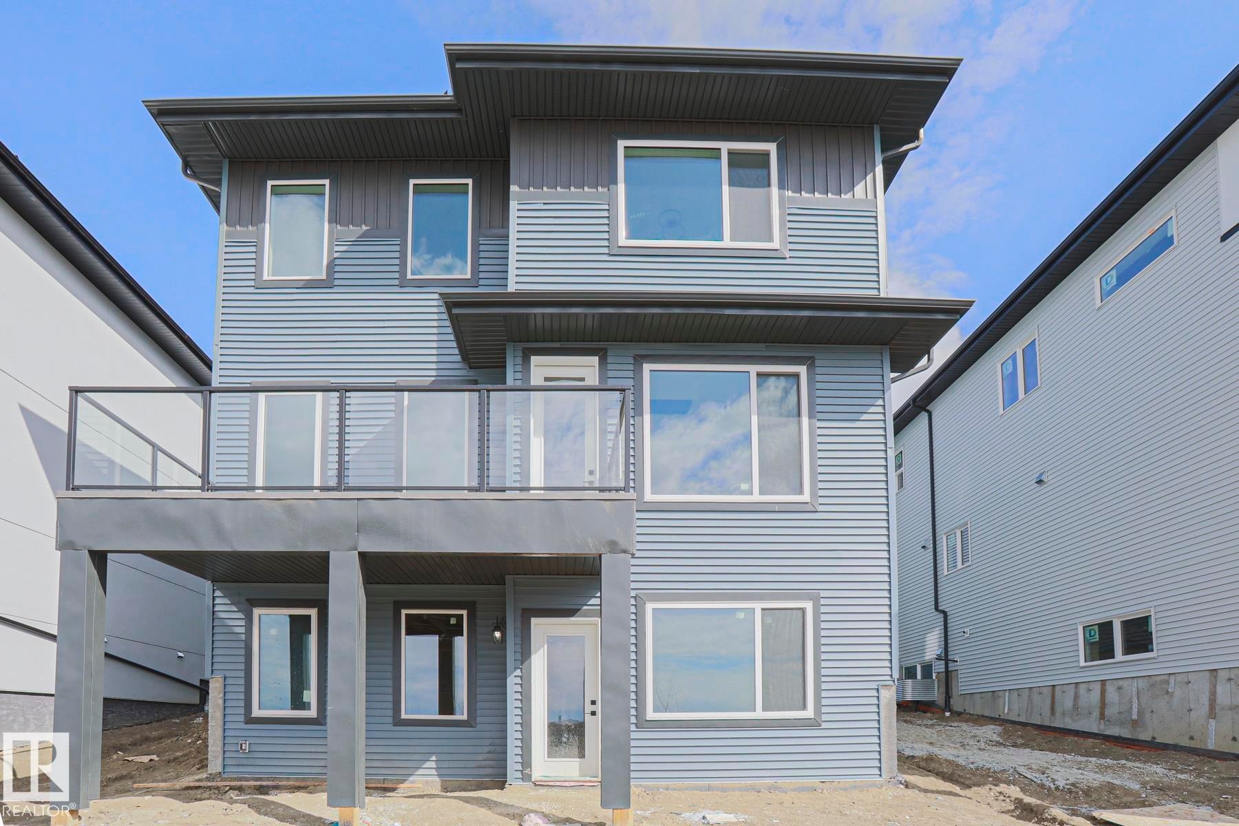 The property features a contemporary exterior with multi-level siding and a second-story balcony with a glass railing - Rural Leduc County, AB - Outdoor