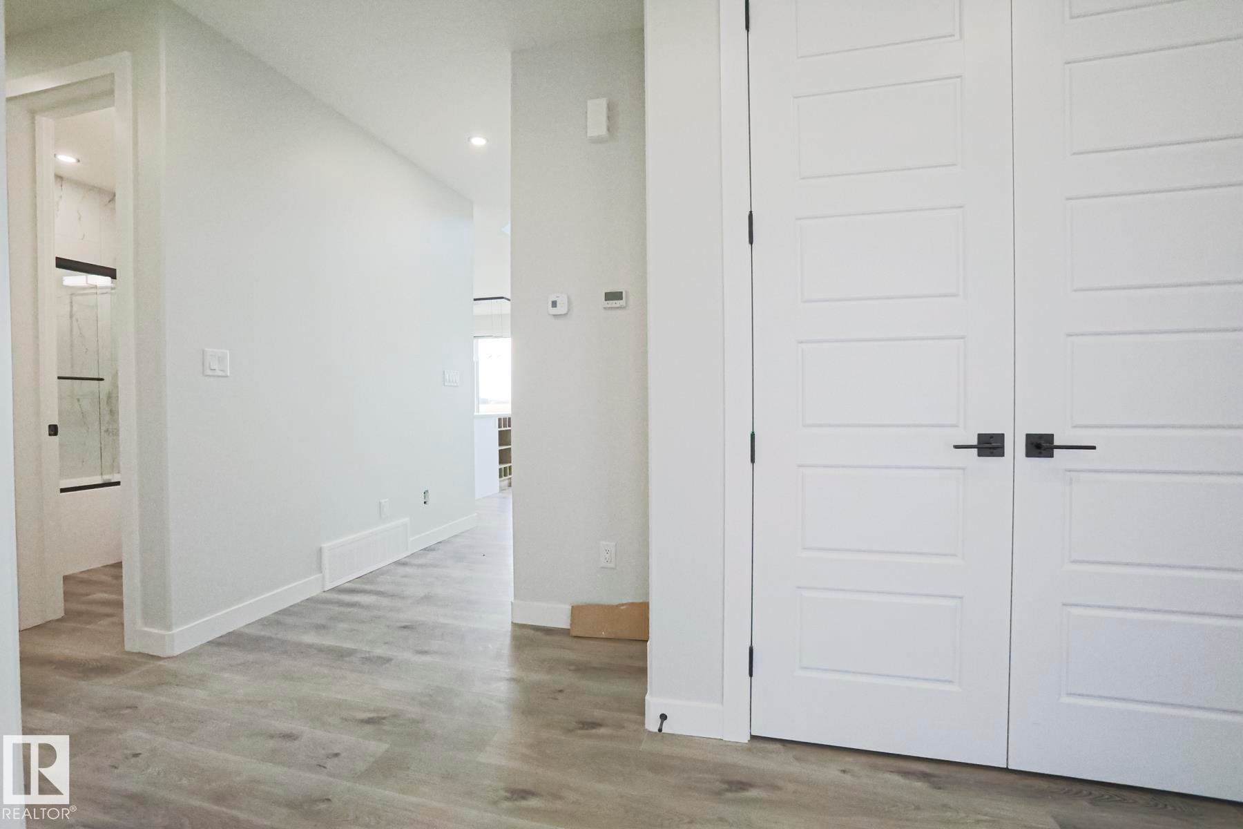 This interior space features light-colored walls and wood-look flooring - Rural Leduc County, AB - Indoor Photo Showing Other Room