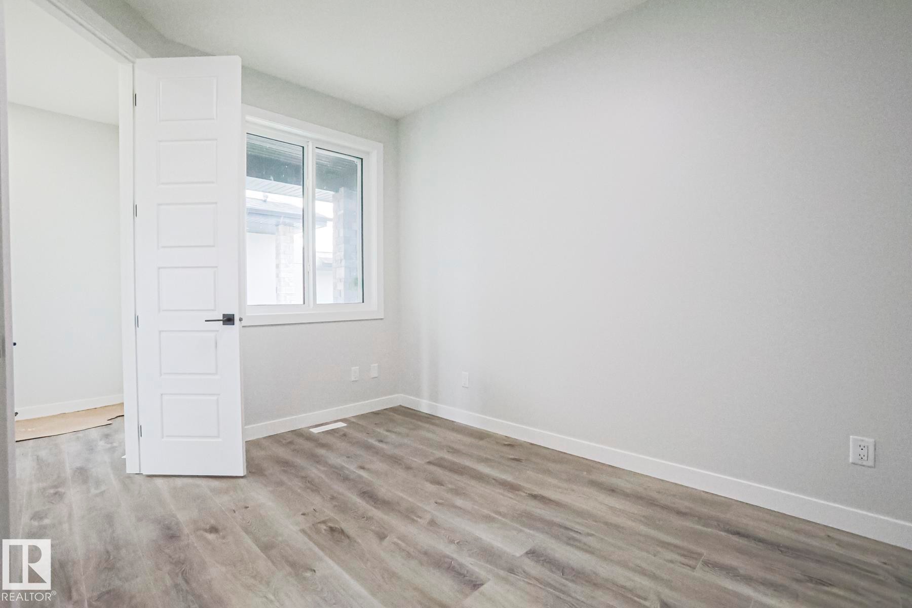 Room featuring light-colored walls, wood-style flooring, and a window providing natural light - Rural Leduc County, AB - Indoor Photo Showing Other Room