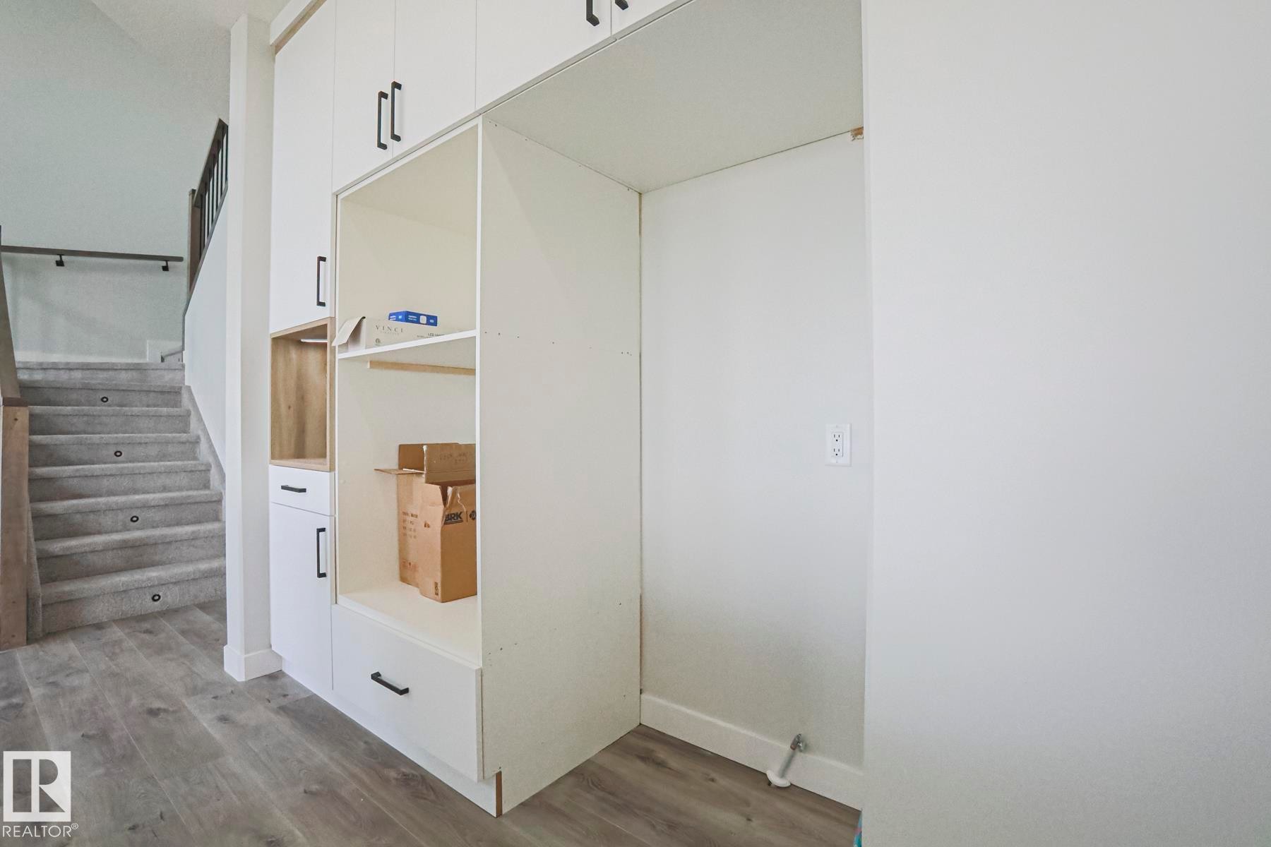 This entry area features built-in white cabinetry with black hardware, providing storage solutions - Rural Leduc County, AB - Indoor Photo Showing Other Room