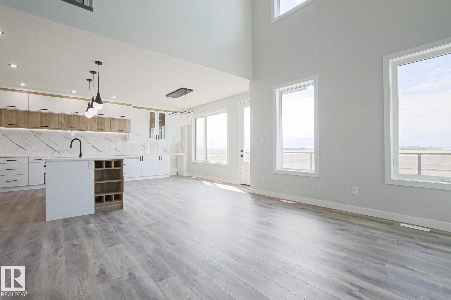 Open concept living area featuring light wood-style flooring and high ceilings - Rural Leduc County, AB - Indoor