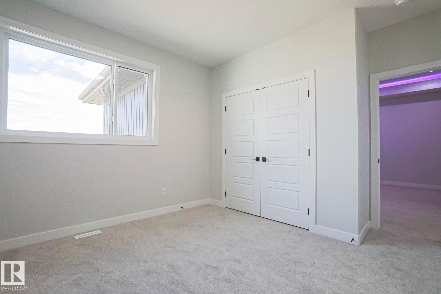 Bright room featuring light gray walls, light gray carpeting, and a white window frame - Rural Leduc County, AB - Indoor