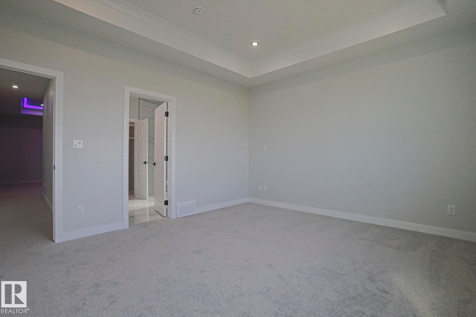 Spacious room featuring light grey carpeting, white walls, and a tray ceiling with recessed lighting - Rural Leduc County, AB - Indoor Photo Showing Other Room