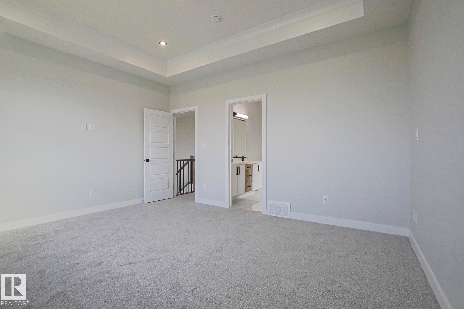 Spacious room featuring light grey carpet flooring, light grey walls, and a recessed ceiling with crown molding and integrated lighting - Rural Leduc County, AB - Indoor Photo Showing Other Room