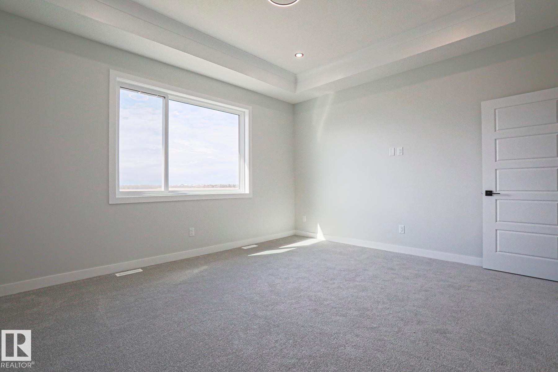 Bright room featuring light grey carpeting, white walls, and a large window providing natural light - Rural Leduc County, AB - Indoor Photo Showing Other Room