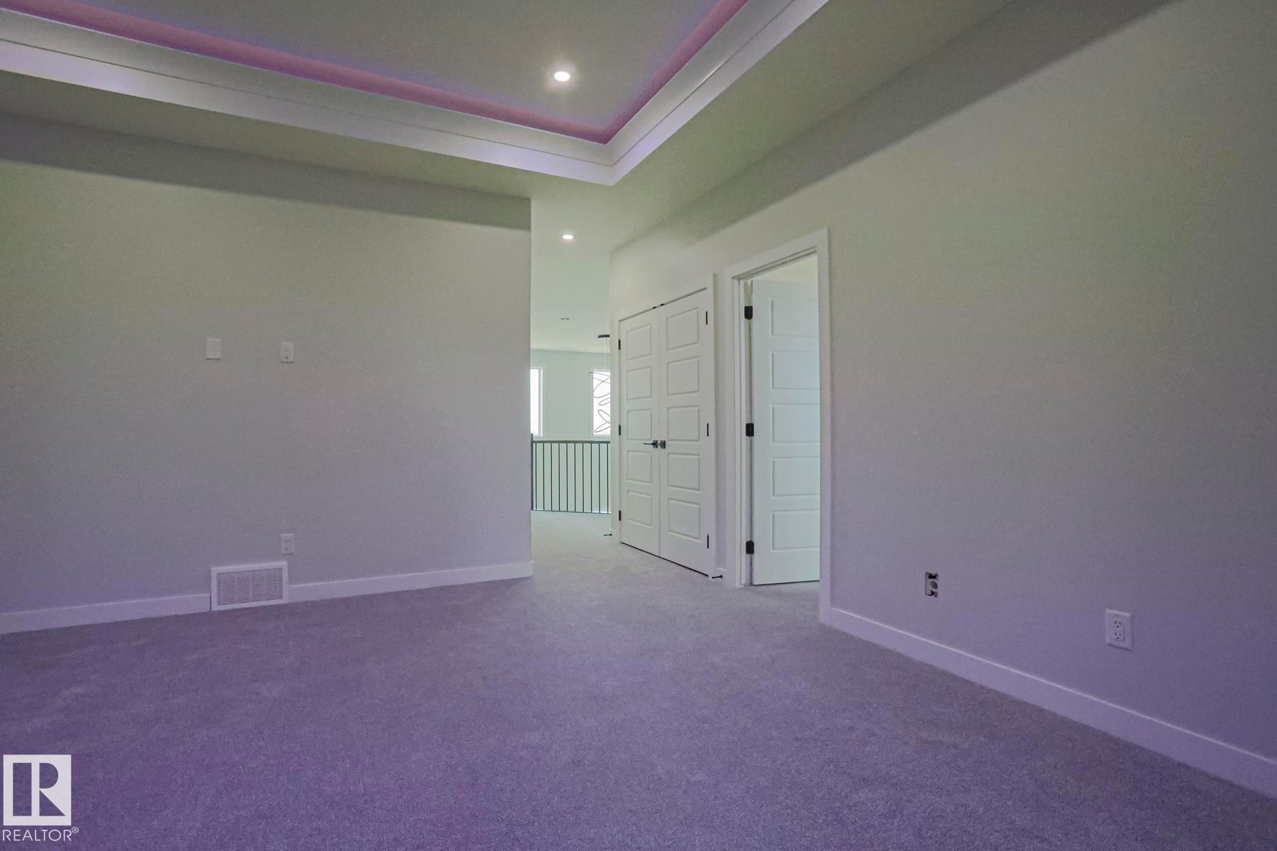 Spacious room featuring light-colored carpet, white baseboards, and a tray ceiling with recessed lighting - Rural Leduc County, AB - Indoor Photo Showing Other Room