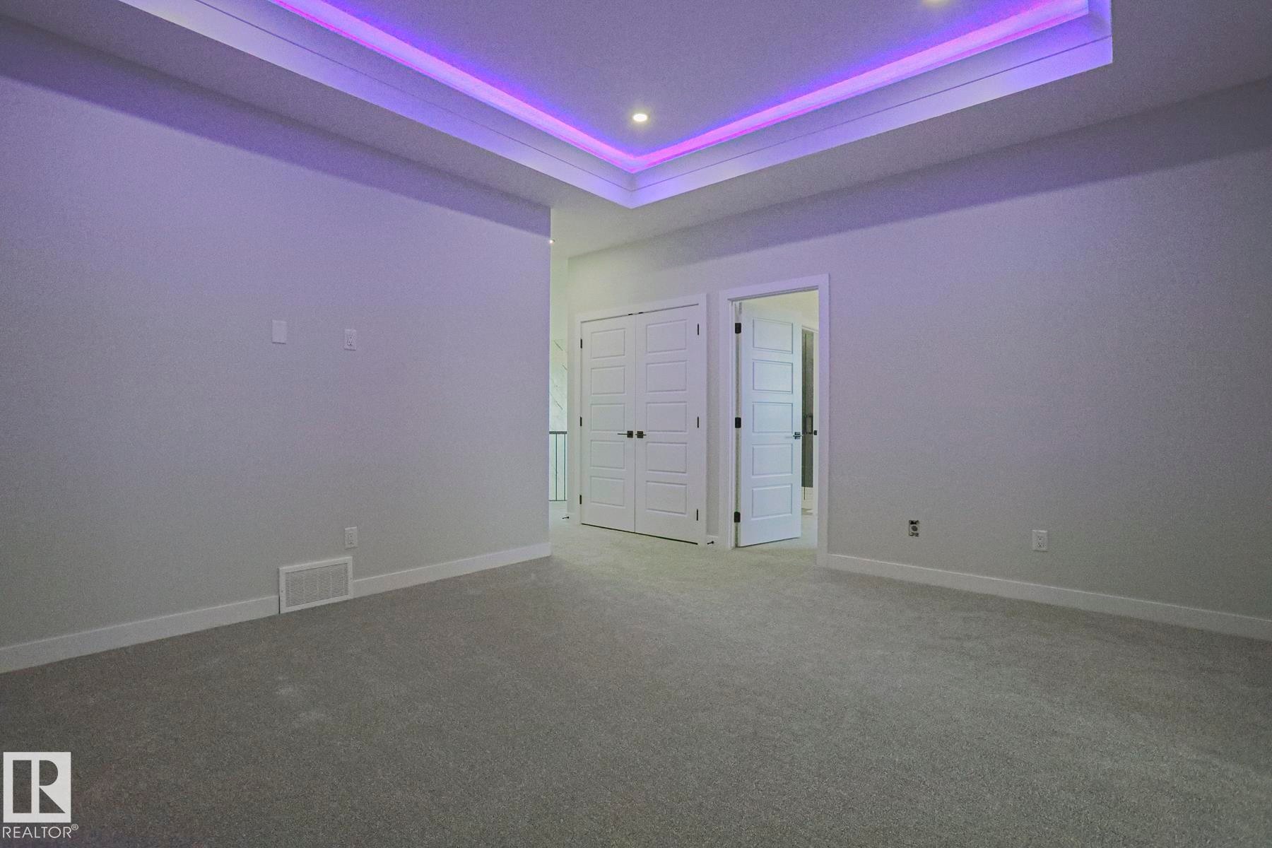 This room features a tray ceiling with accent lighting, recessed ceiling lights, and carpeted flooring - Rural Leduc County, AB - Indoor Photo Showing Other Room
