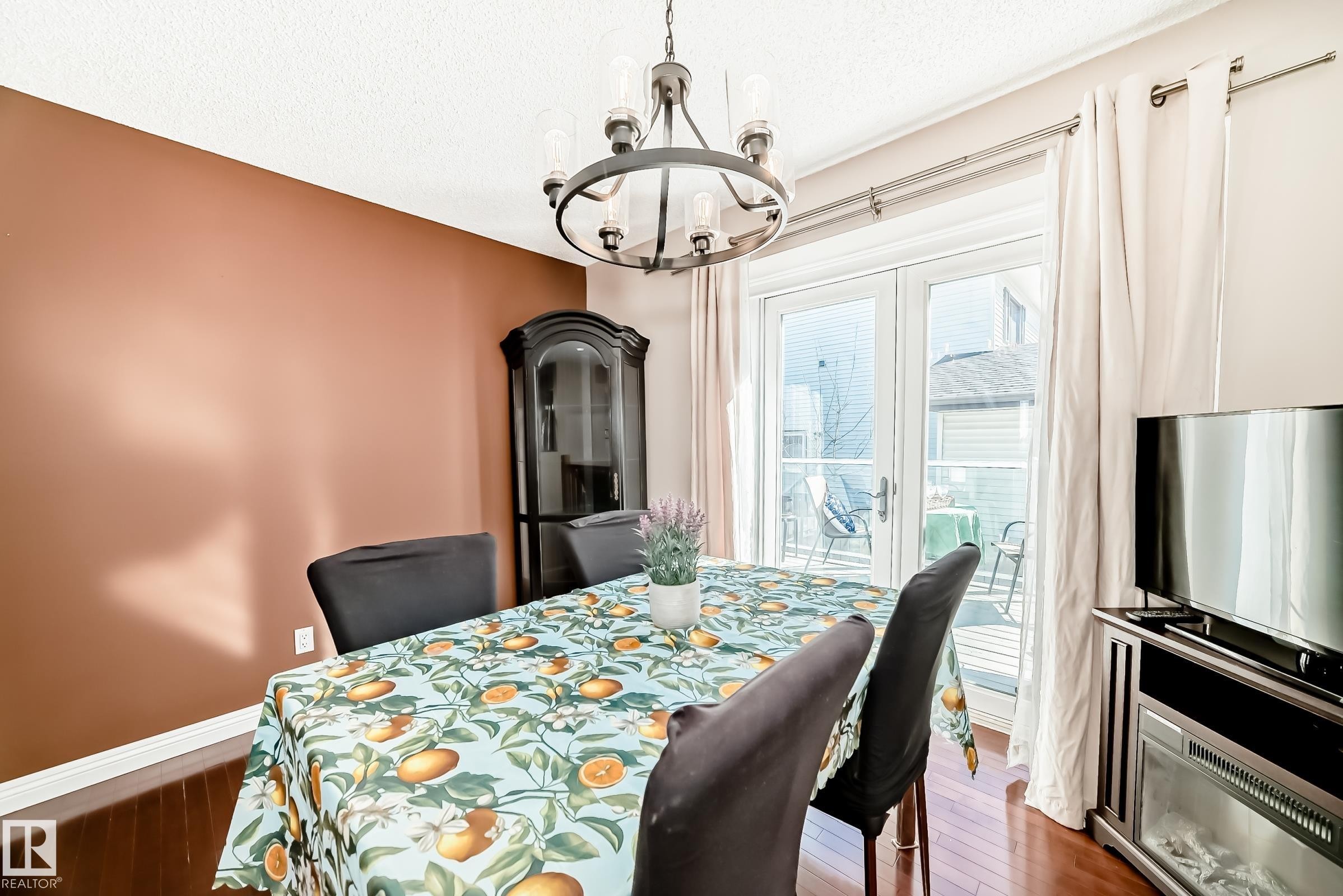 Dining area featuring hardwood floors, a modern chandelier, and access to an outdoor area through double doors - 287 Lago Lindo Crescent, Edmonton, AB - Indoor Photo Showing Dining Room
