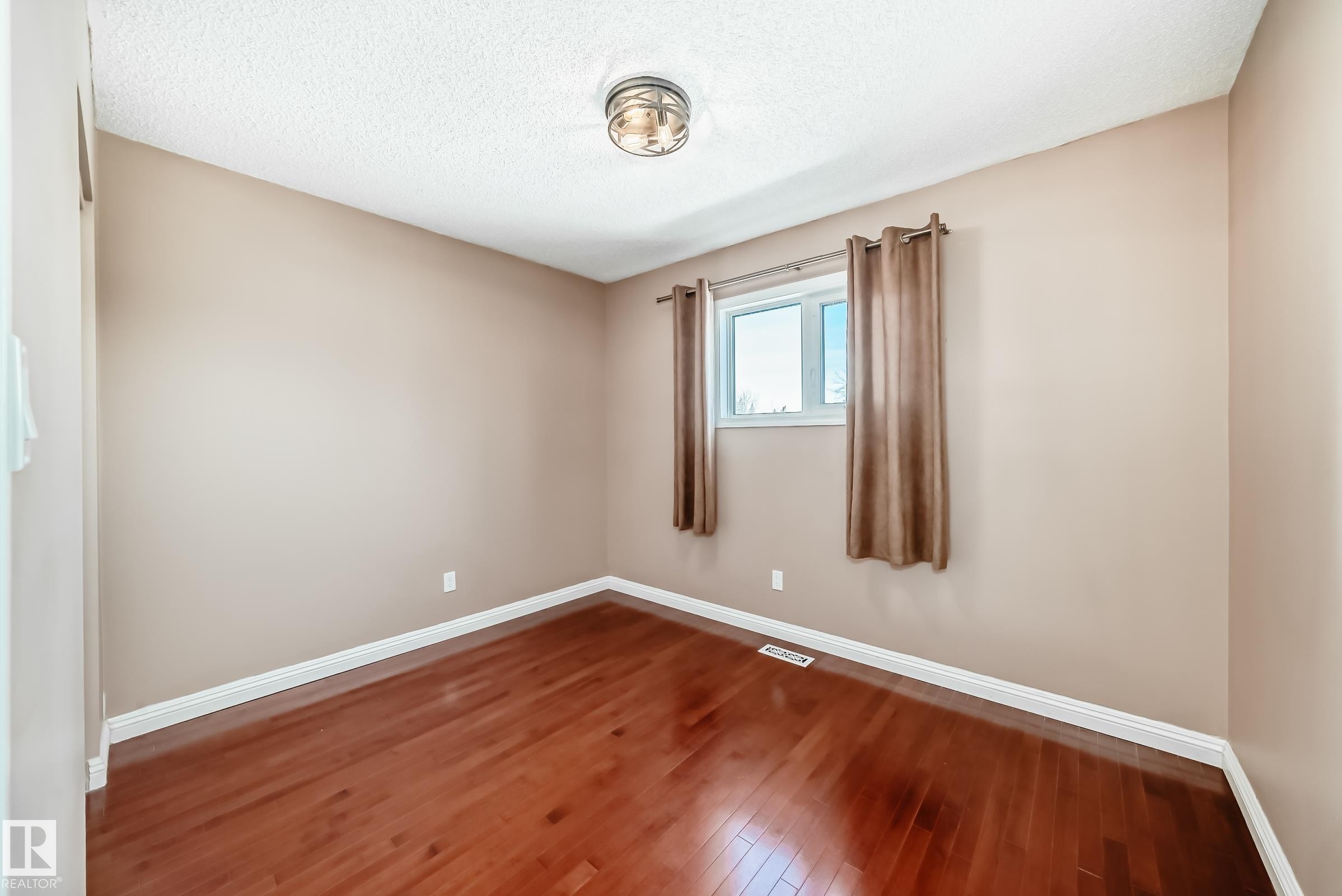 Room featuring rich hardwood floors, a window with curtains, and a ceiling light fixture - 287 Lago Lindo Crescent, Edmonton, AB - Indoor Photo Showing Other Room
