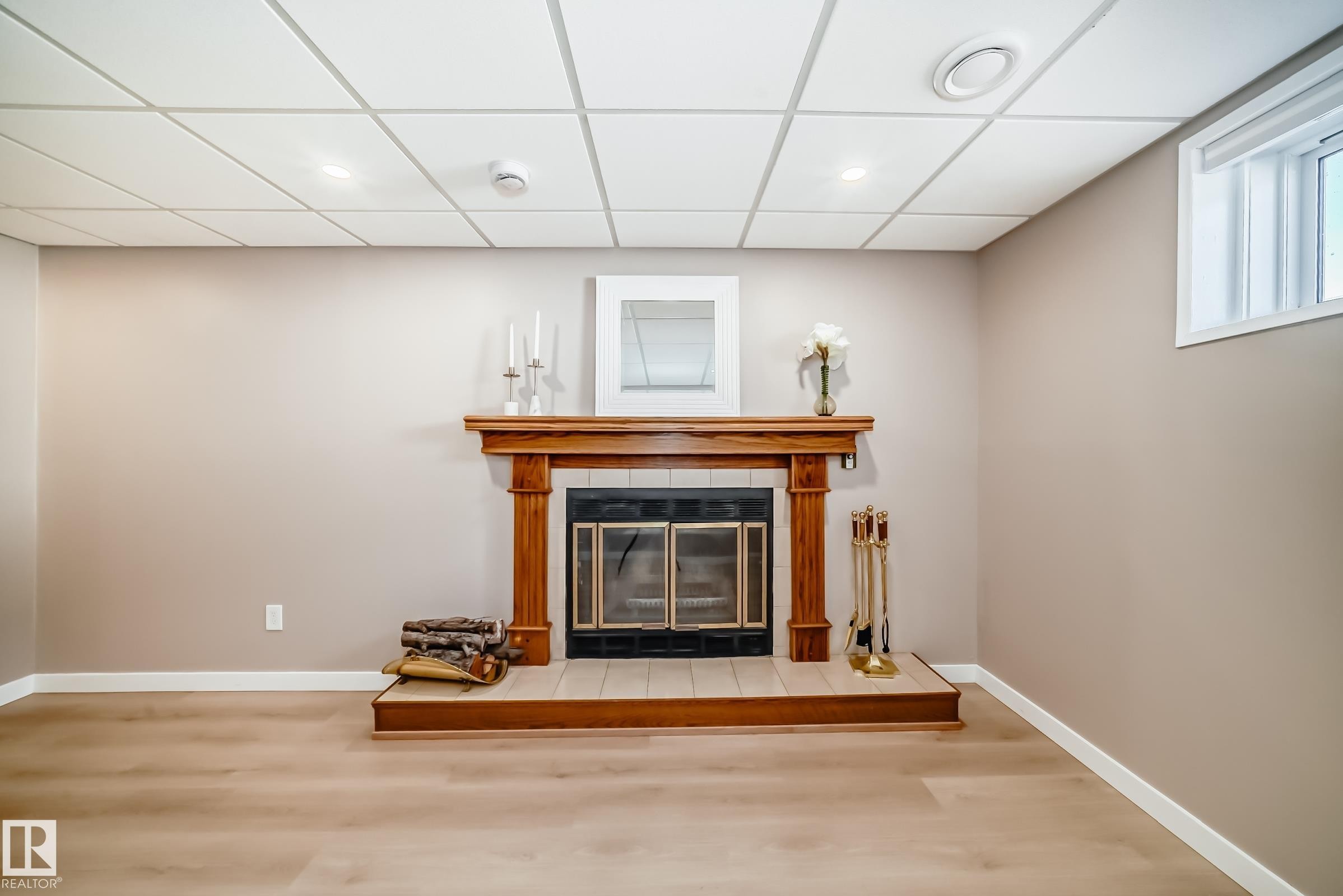 This room features a classic wooden fireplace with a black insert, light-toned walls, and light wood flooring - 287 Lago Lindo Crescent, Edmonton, AB - Indoor Photo Showing Other Room With Fireplace