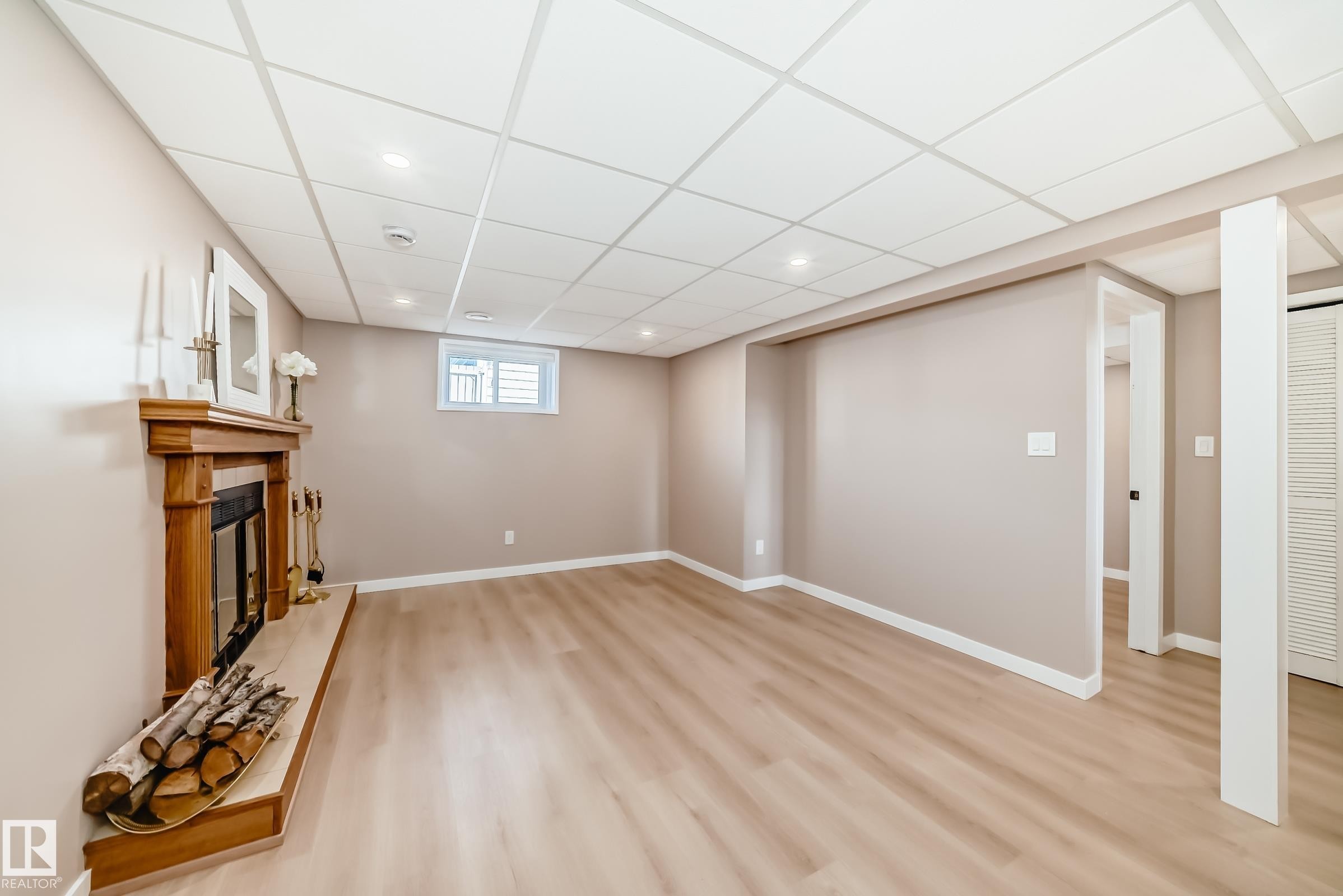 Living area featuring light wood-tone flooring, a fireplace with a wood mantle, and a drop ceiling with recessed lighting - 287 Lago Lindo Crescent, Edmonton, AB - Indoor