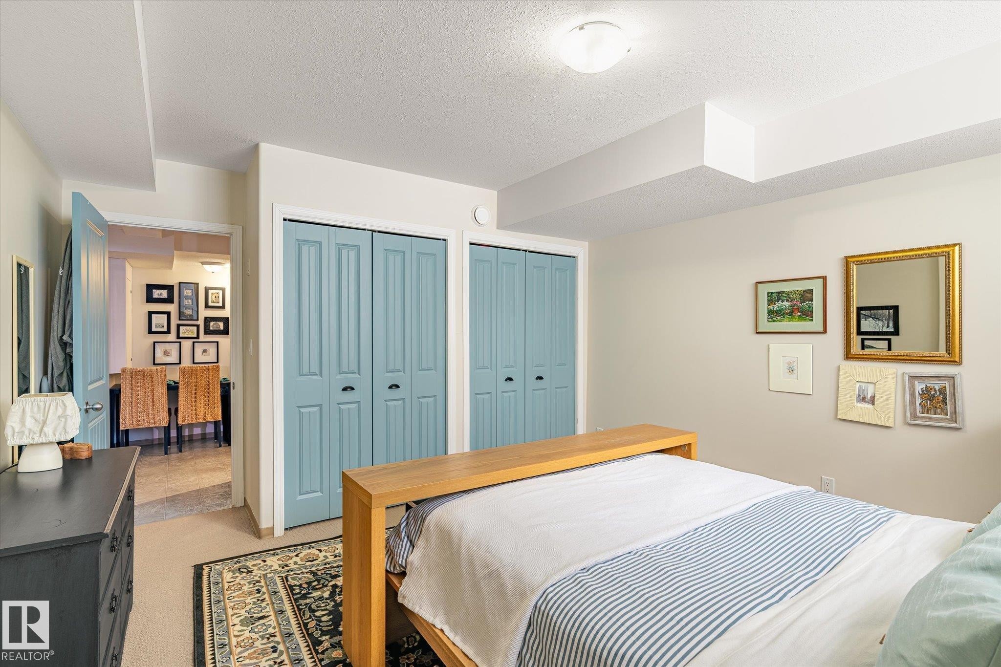 This room features neutral-toned walls, two sets of bi-fold closet doors, and a carpeted floor with an area rug - 5 4902B 43 Street, Legal, AB