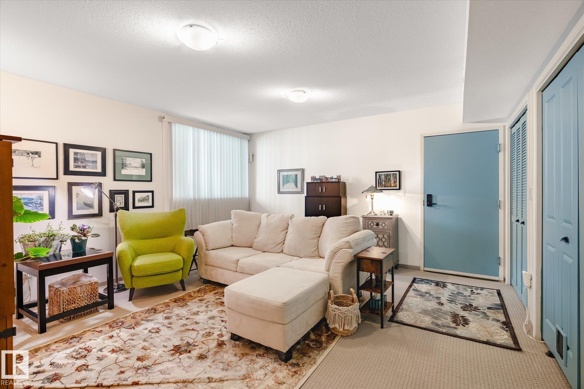 Living area featuring light-colored walls, carpeted flooring, and a window with vertical blinds - 5 4902B 43 Street, Legal, AB