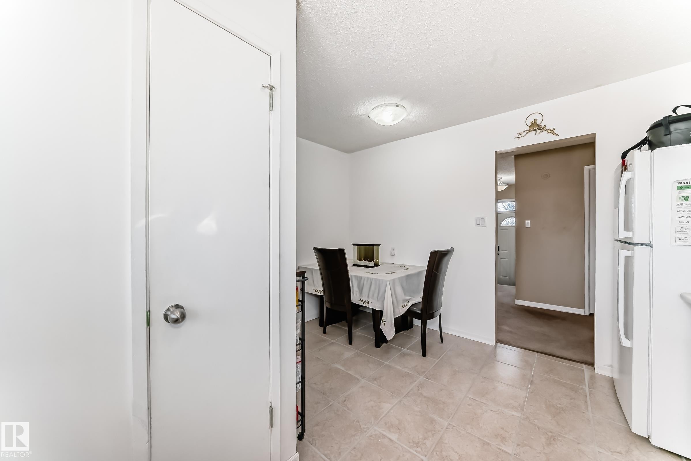 This kitchen features tiled flooring, a ceiling-mounted light fixture, and a refrigerator - 11323 162 Avenue, Edmonton, AB - Indoor