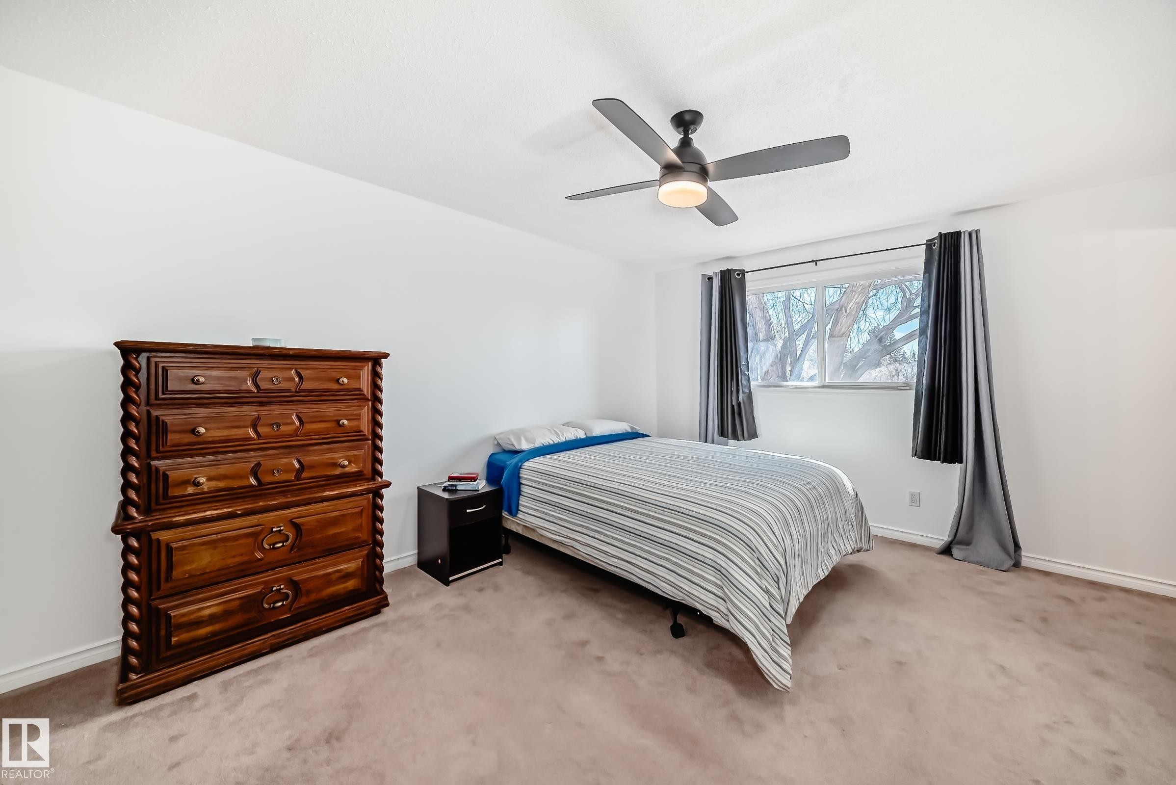 This room features a ceiling fan with integrated lighting, a window with curtains, and carpeting - 11323 162 Avenue, Edmonton, AB - Indoor Photo Showing Bedroom