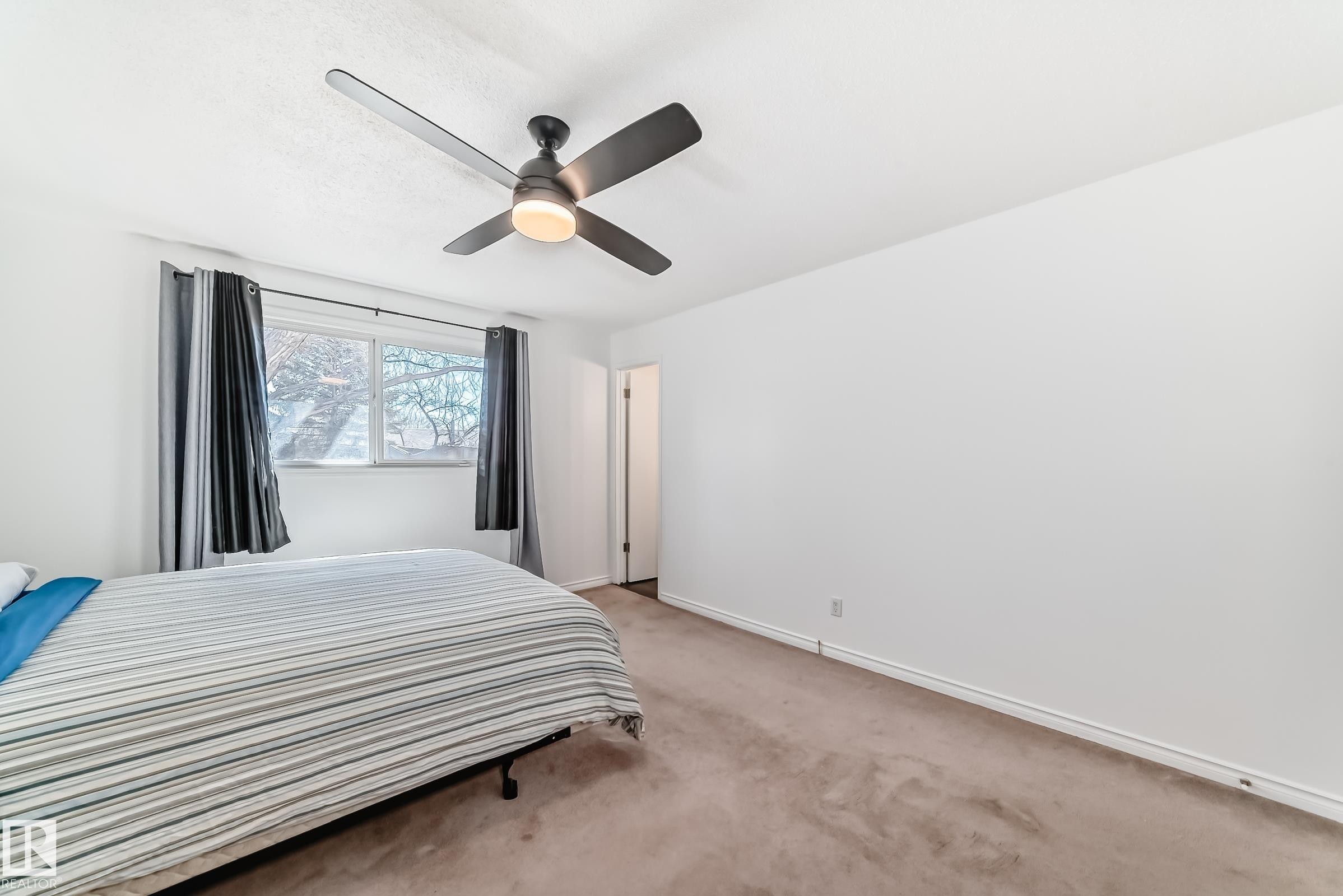 This room features a window providing natural light, neutral carpeting, and a ceiling fan with integrated lighting - 11323 162 Avenue, Edmonton, AB - Indoor Photo Showing Bedroom