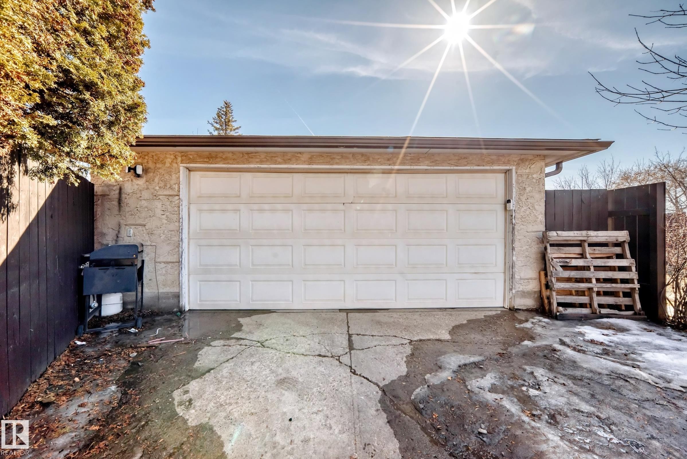 The property features a garage with a white overhead door and a light-colored stucco exterior - 11323 162 Avenue, Edmonton, AB - Outdoor