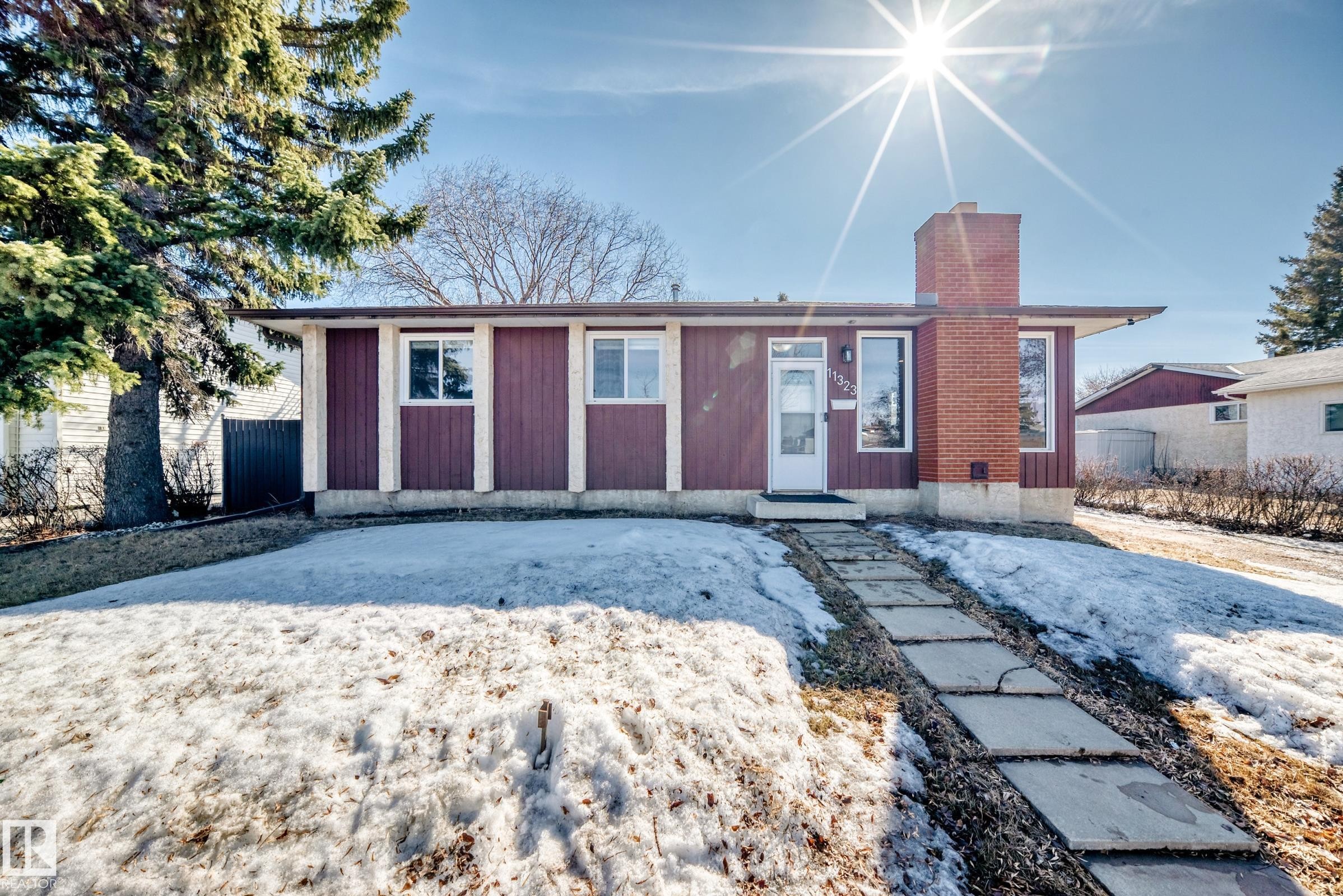 The property features a brick chimney, a white front door, and a concrete slab walkway leading to the entrance - 11323 162 Avenue, Edmonton, AB - Outdoor