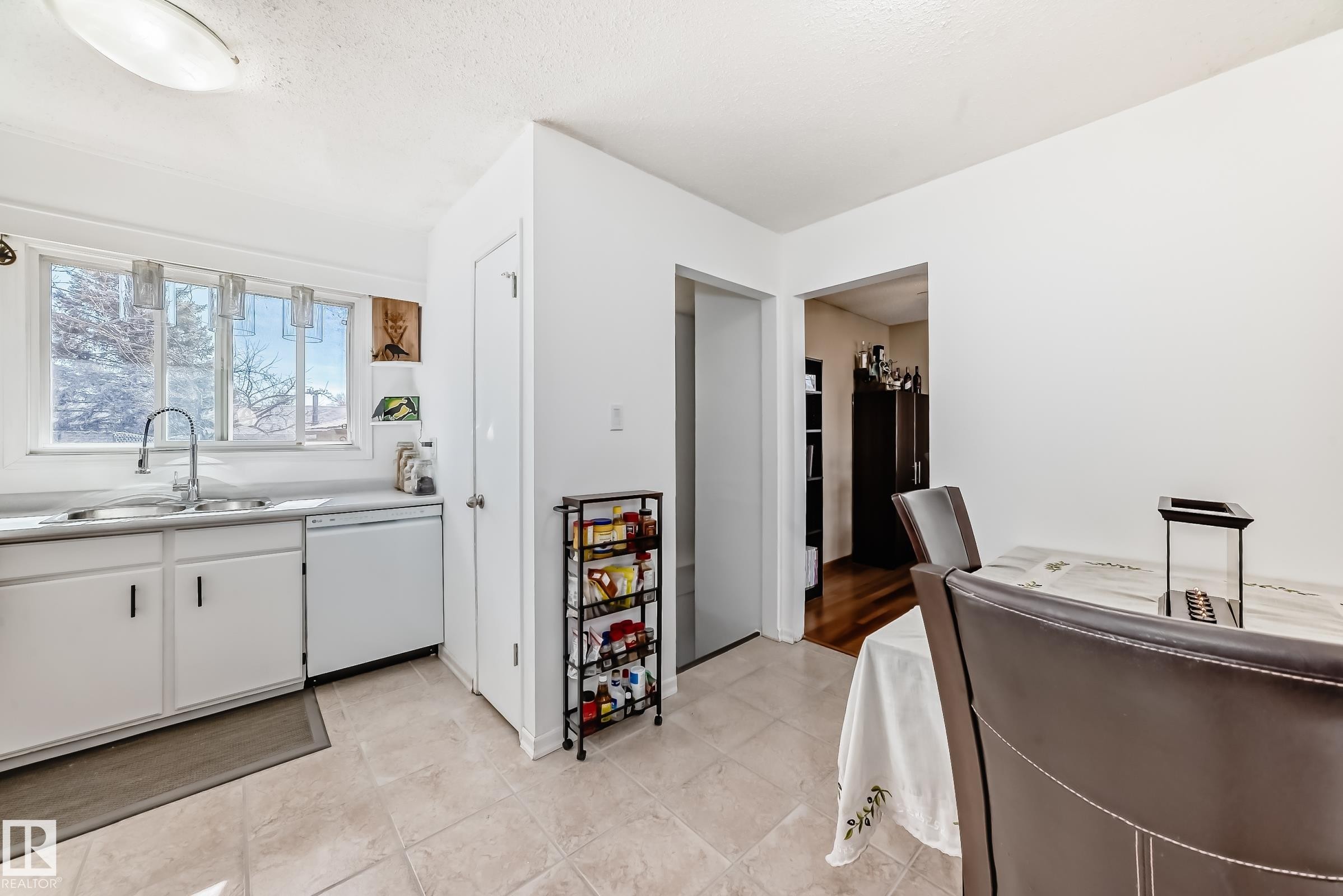 The kitchen features white cabinetry, a double sink with a window view, and a white dishwasher - 11323 162 Avenue, Edmonton, AB - Indoor Photo Showing Kitchen