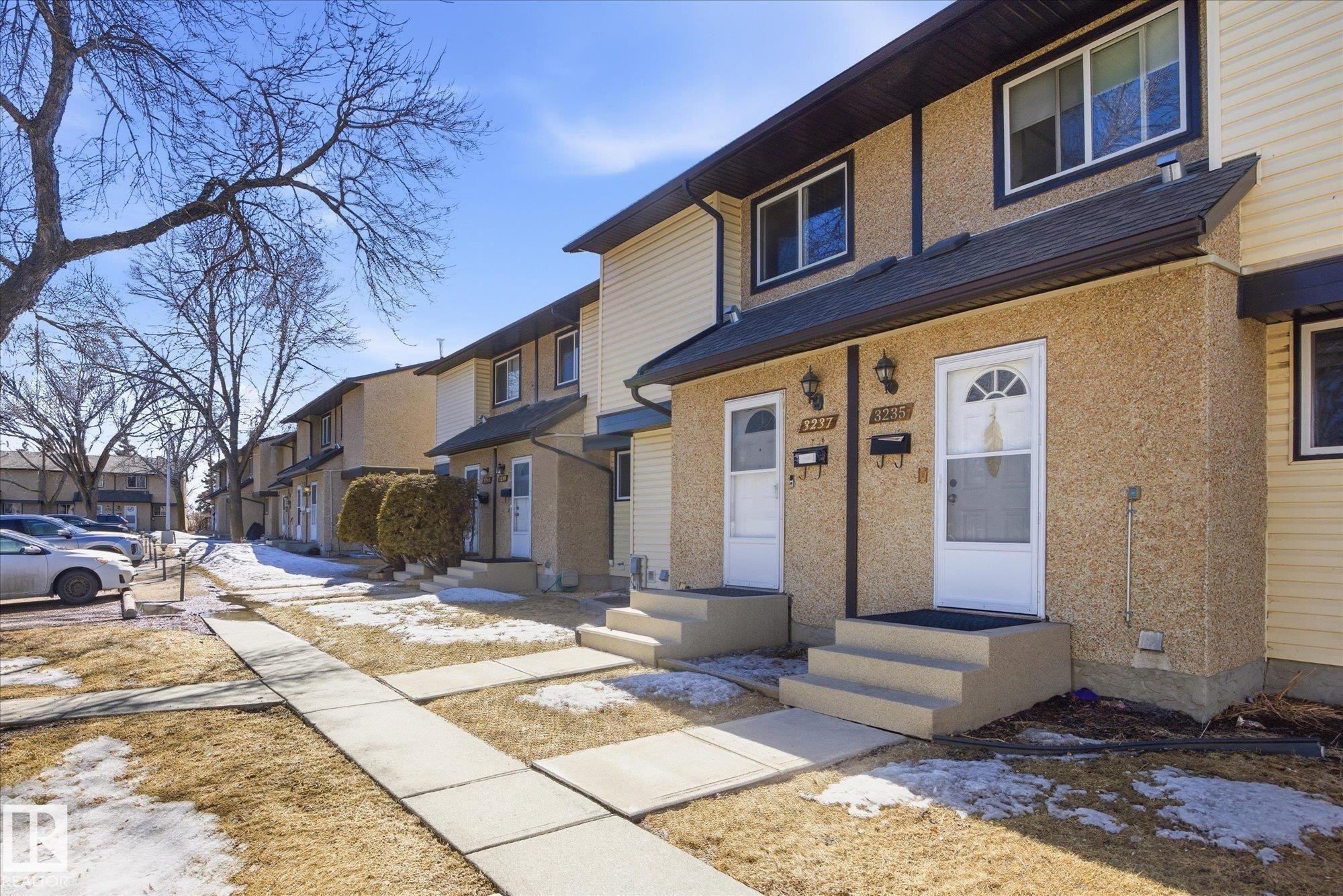 The property features a two-story exterior with light-colored stucco and siding, dark trim, and a dark shingled roof - 3237 142 Avenue, Edmonton, AB - Outdoor With Exterior