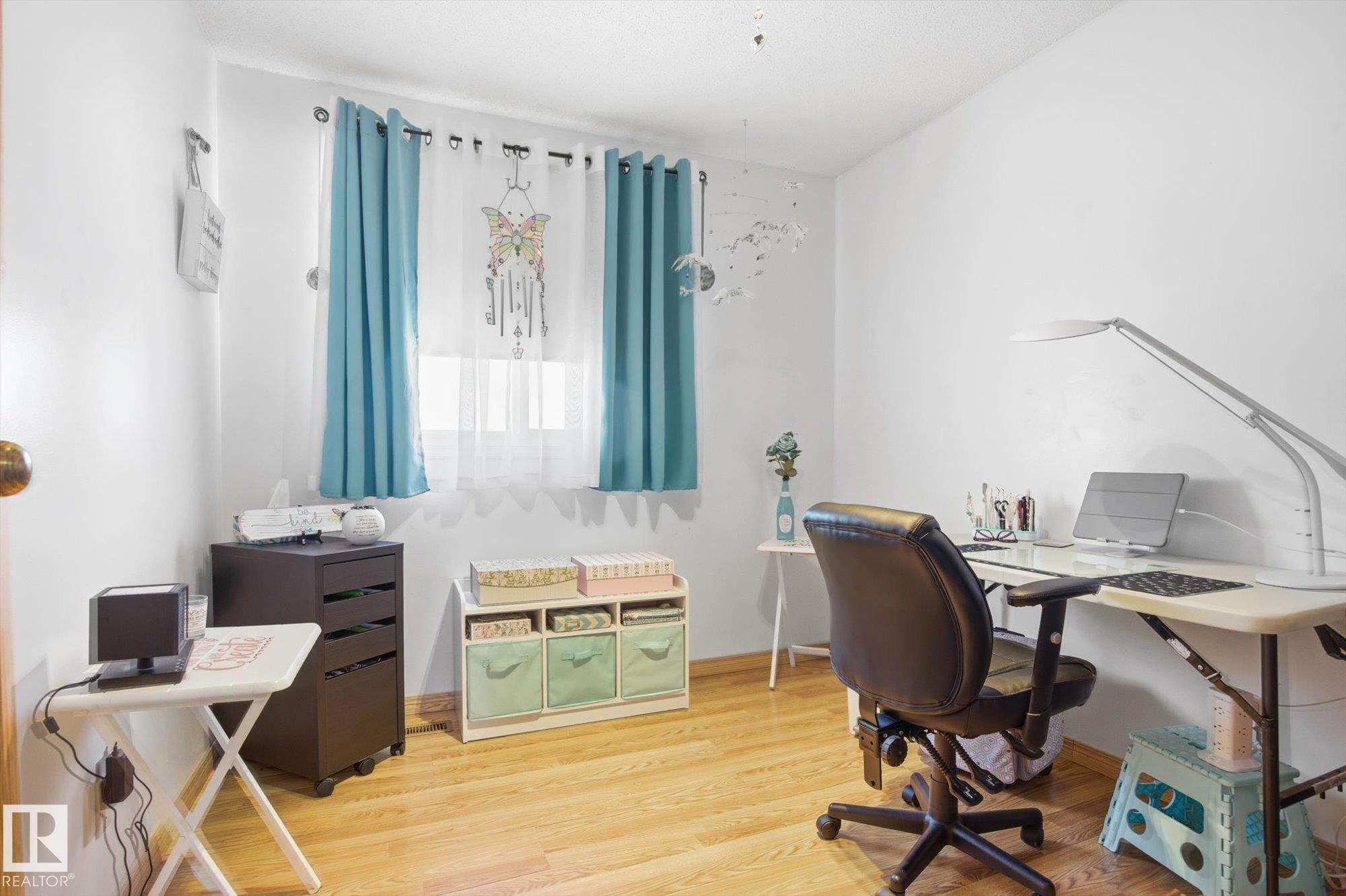 This room features a window with curtains, light wood flooring, and white walls - 3237 142 Avenue, Edmonton, AB - Indoor Photo Showing Office