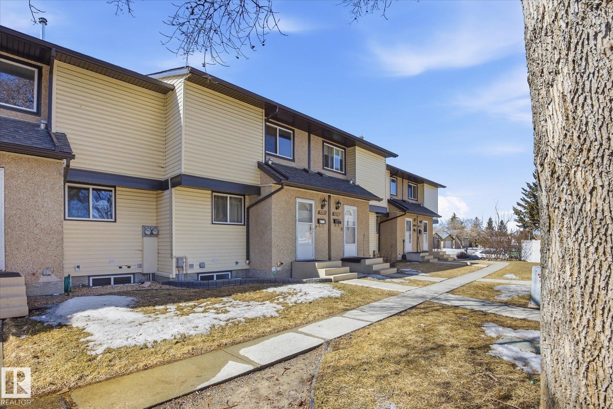 The property features a row of homes with light-colored siding, dark roofs, and multiple windows - 3237 142 Avenue, Edmonton, AB - Outdoor
